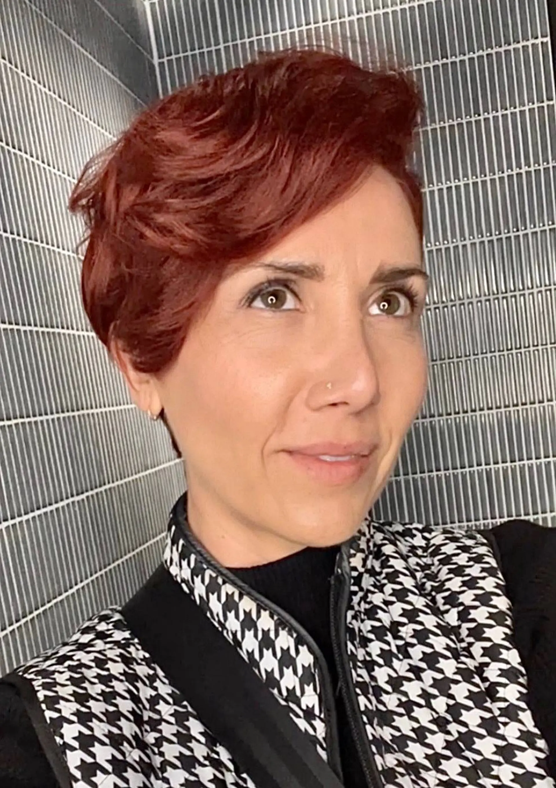 A textured short pixie cut styled with sweeping side-parted volume in a rich auburn-red tone. 1