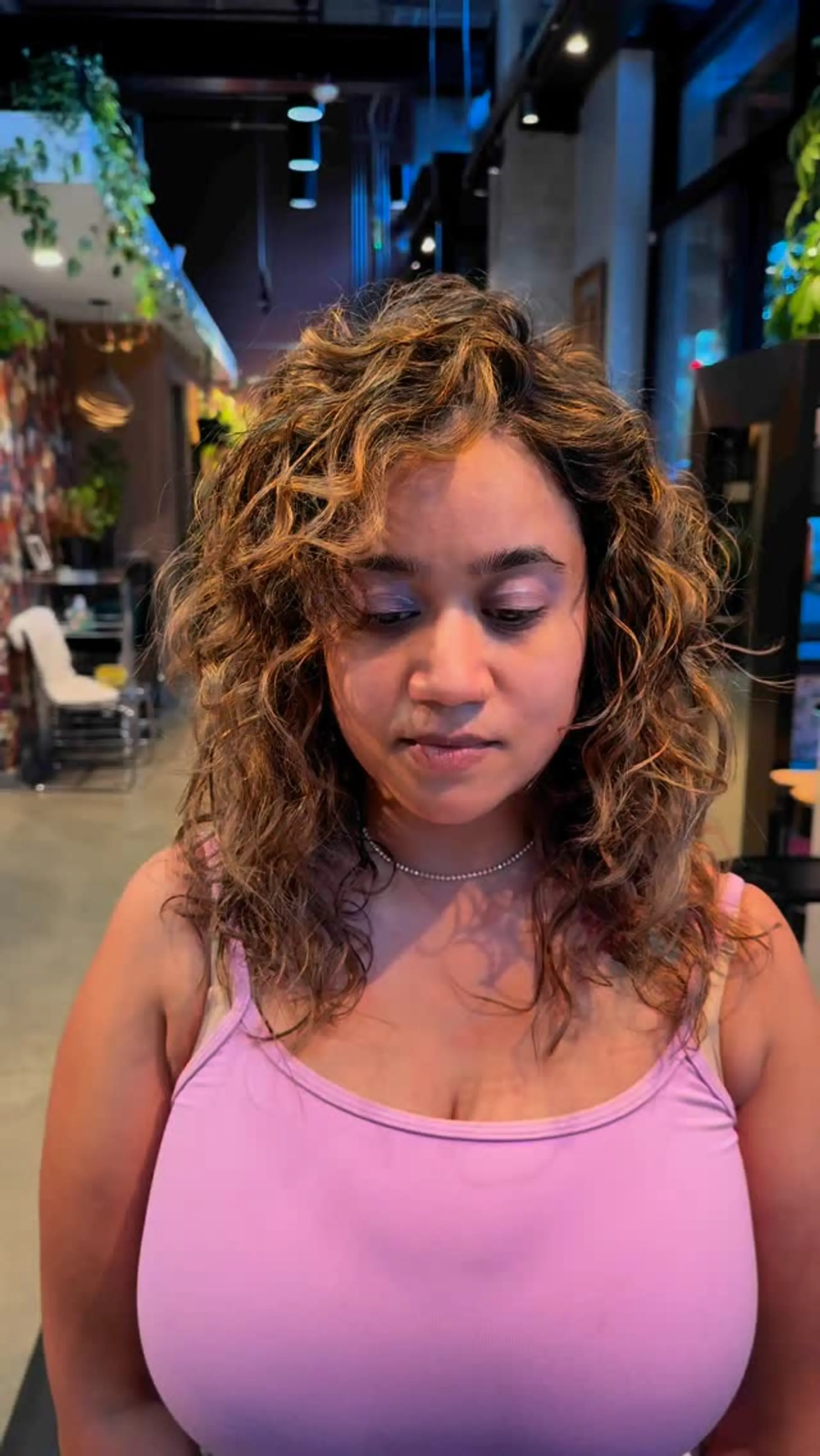 Medium-length textured curly hair featuring warm caramel and honey blonde dimensional highlights. 1