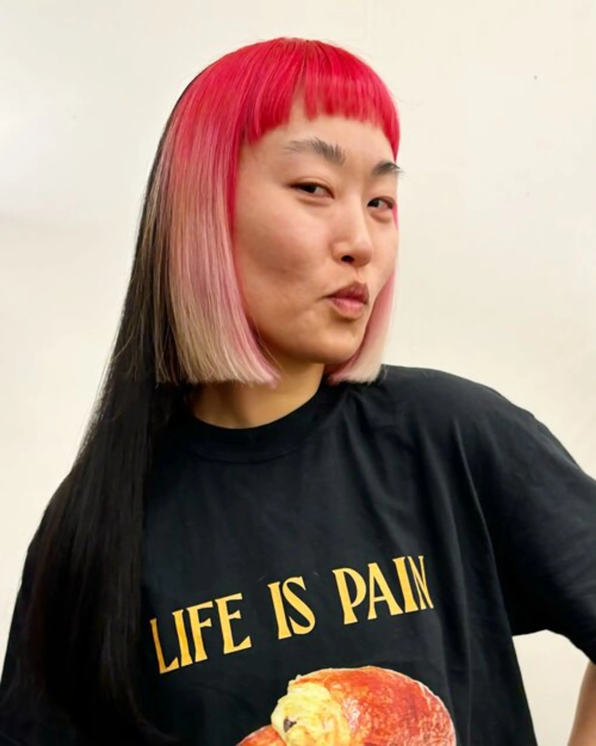 An edgy, medium-length, straight hairstyle with a split dye of jet black and blonde transitioning into bright pink roots, accented with blunt bangs. Haircut and color by @takeohair