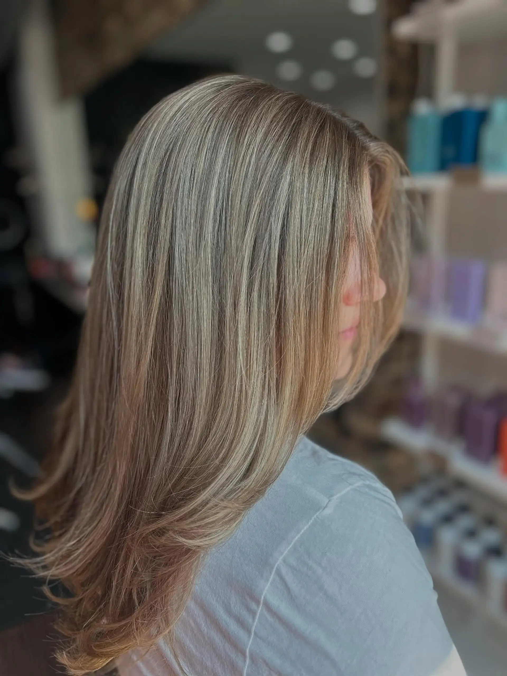 Medium-length straight hair styled with soft, subtle layers that frame the face, enhanced by a dimensional blonde balayage with a blend of ash and golden tones. 1