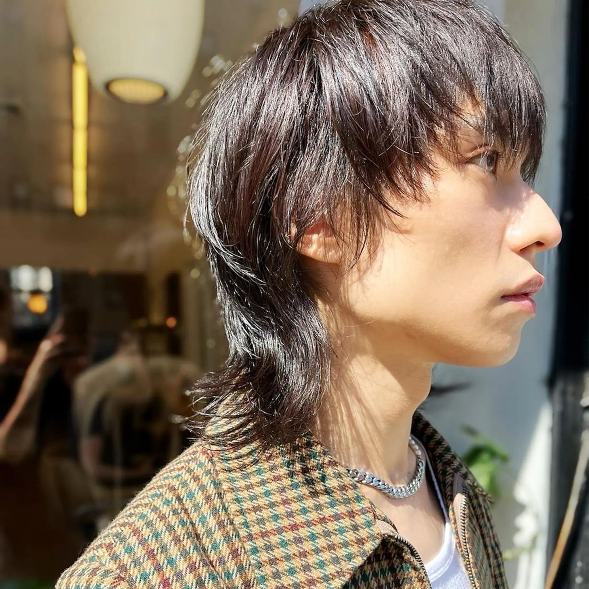 Dark brown, medium-length hair styled in an edgy modern mullet with layered, wavy texture and tapered sides. haircut by @kotarohair.newyork 2