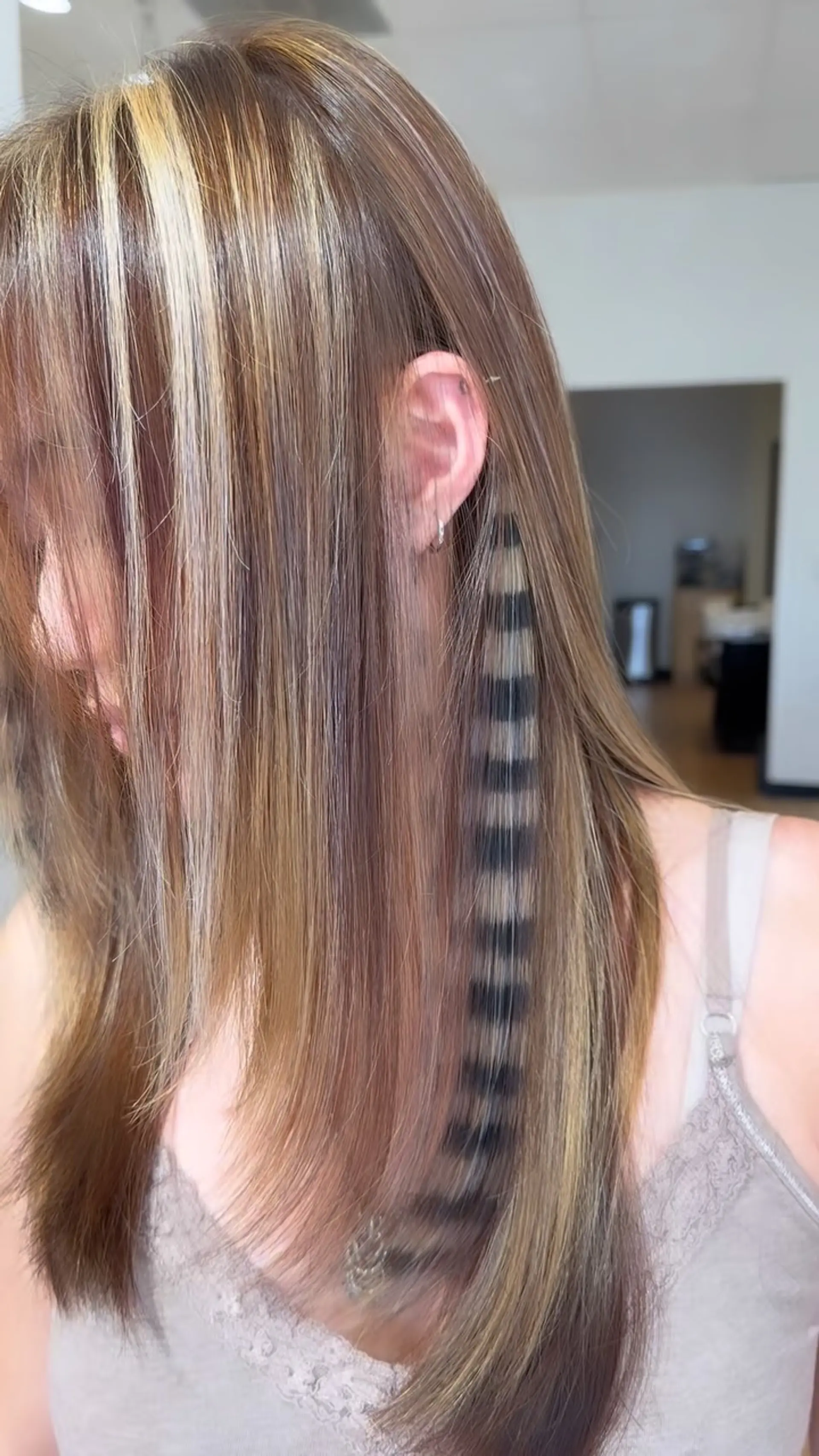 Straight multi-toned brown hair featuring chunky blonde face-framing highlights and an edgy black-and-blonde raccoon tail striped peekaboo strand. 1