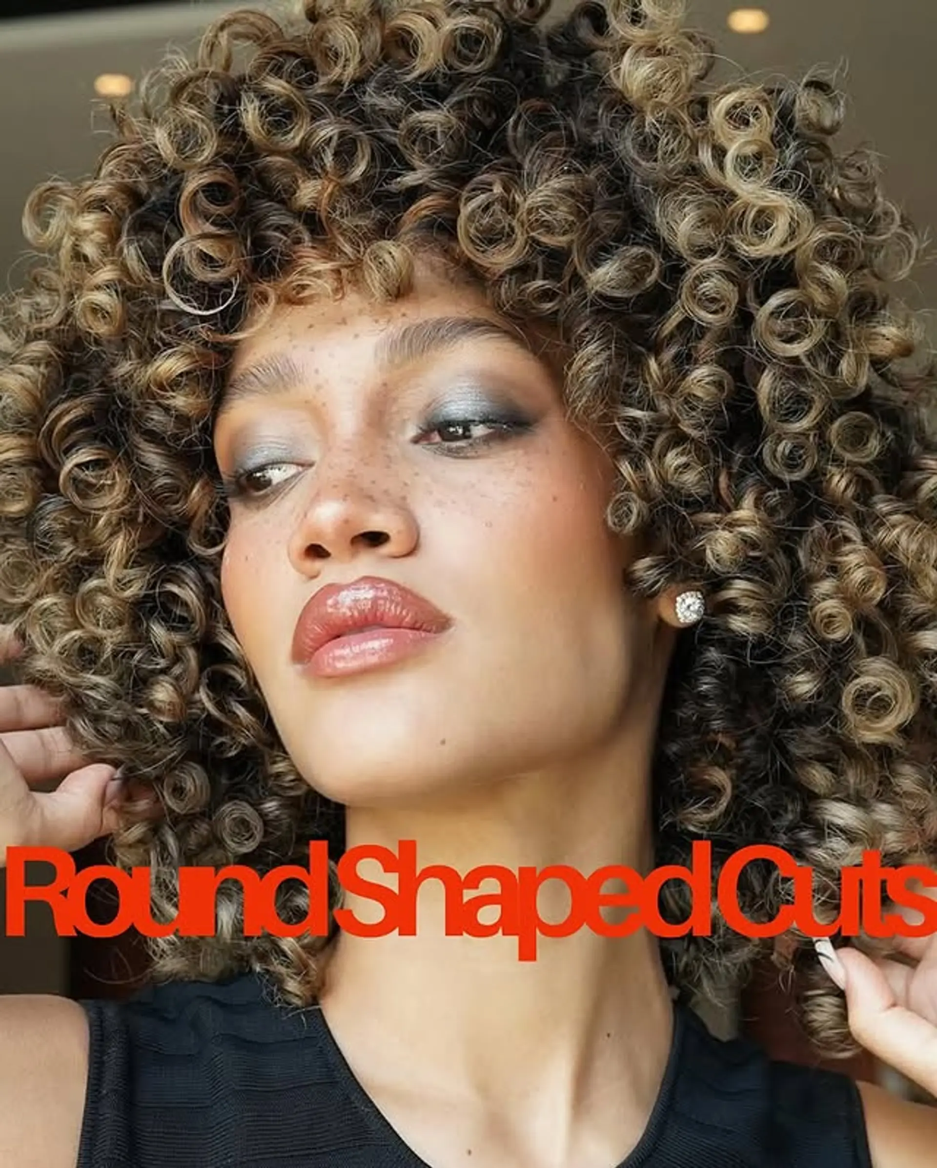 A voluminous afro with defined curls and highlights that accentuate the natural texture and shape. 1