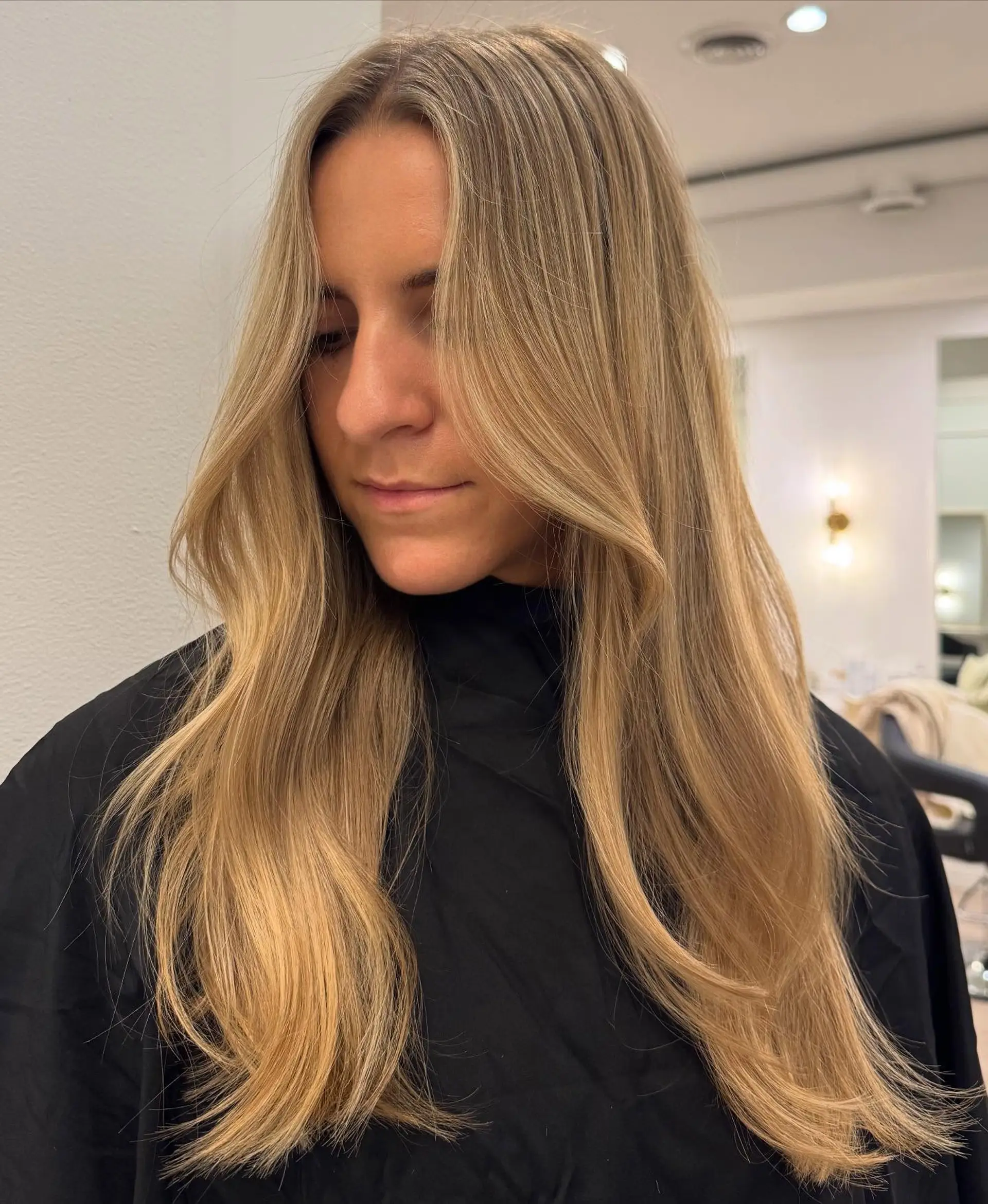 A long, layered haircut with a middle part, showcasing face-framing layers that gently sweep away from the face. The ends are subtly layered to add movement and body, styled with soft, natural waves. 1