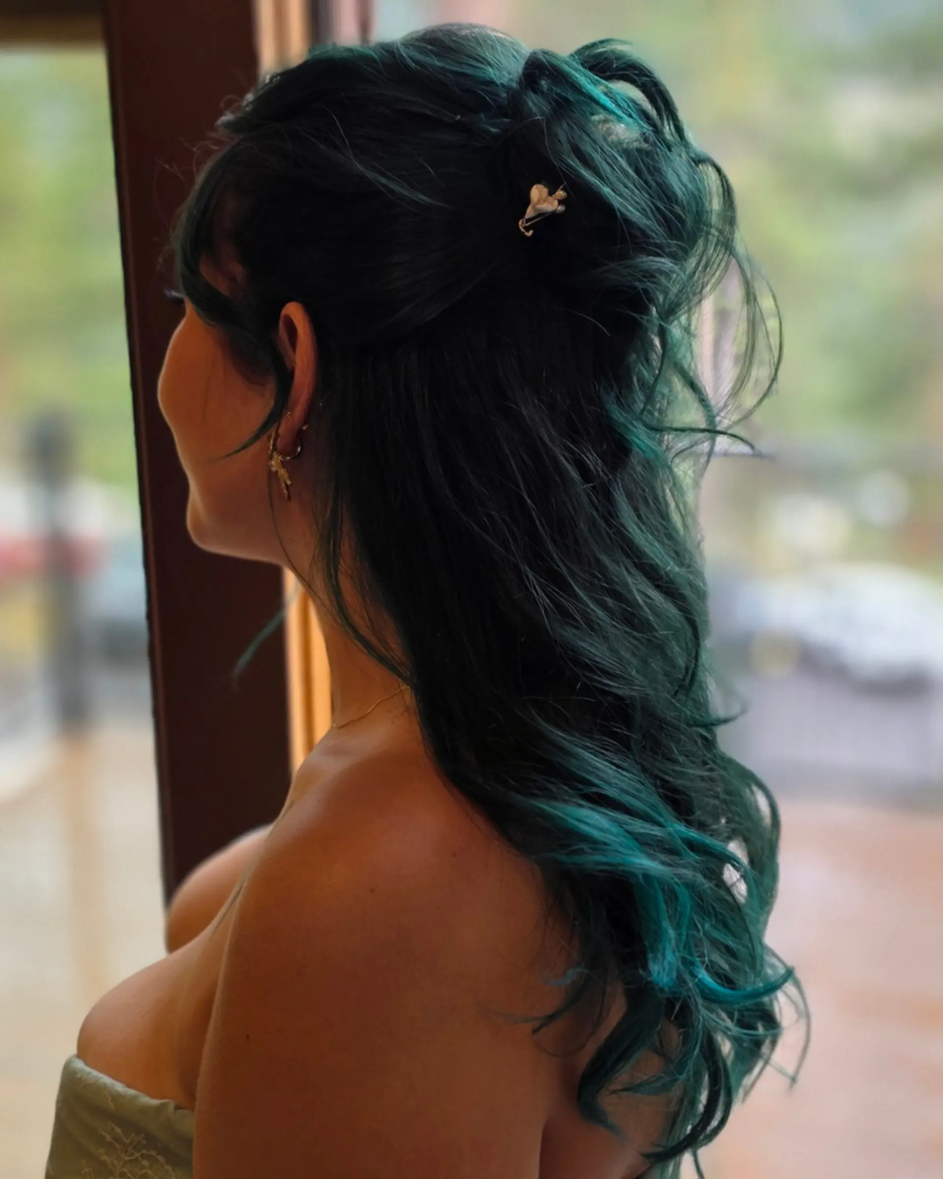 A romantic half-up style featuring vivid teal and emerald green hair styled into soft, textured waves with a decorative hair accessory. 1