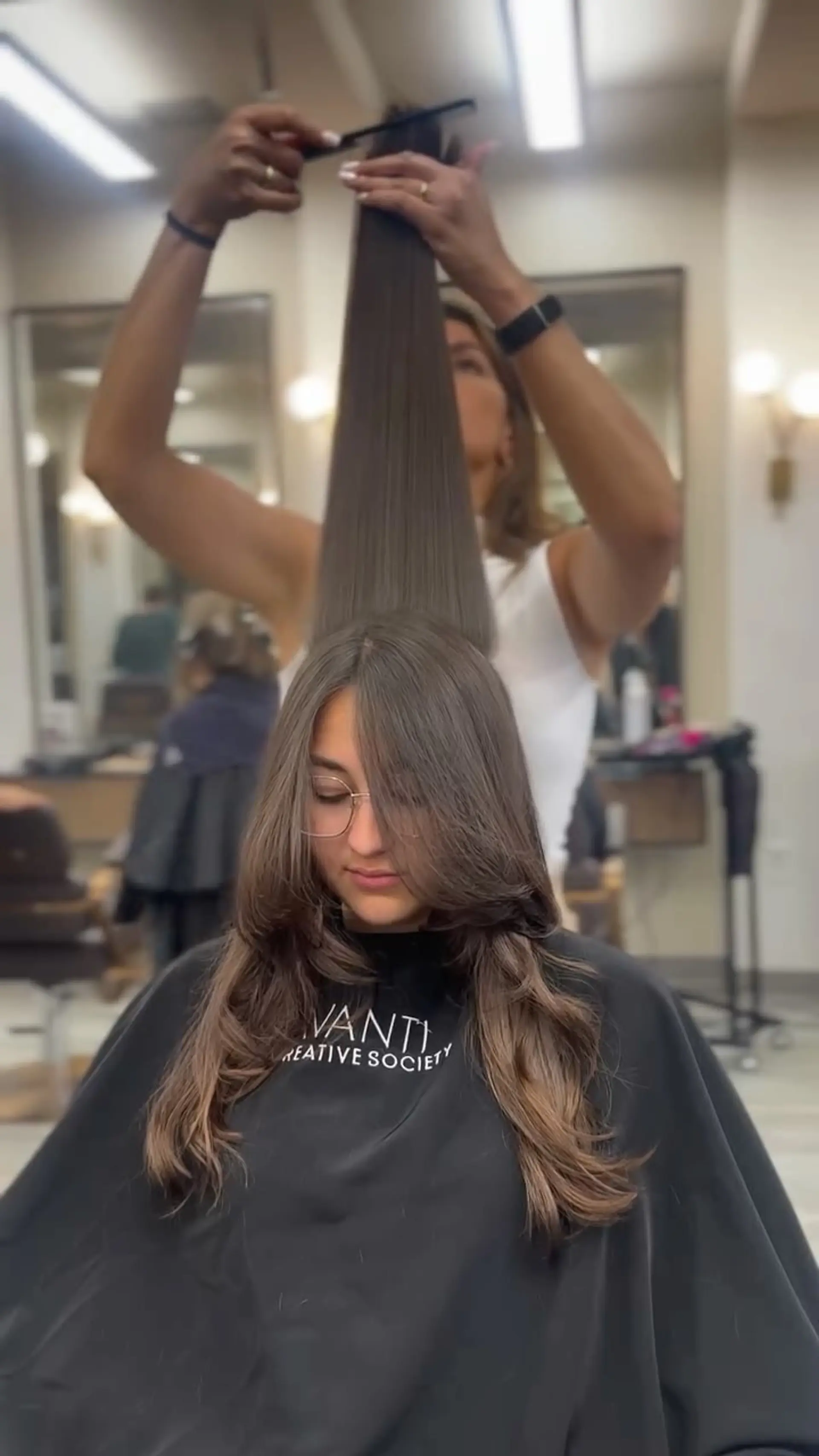 Long layered brunette haircut featuring soft face-framing layers, curtain bangs, and subtle waves at the ends. 1