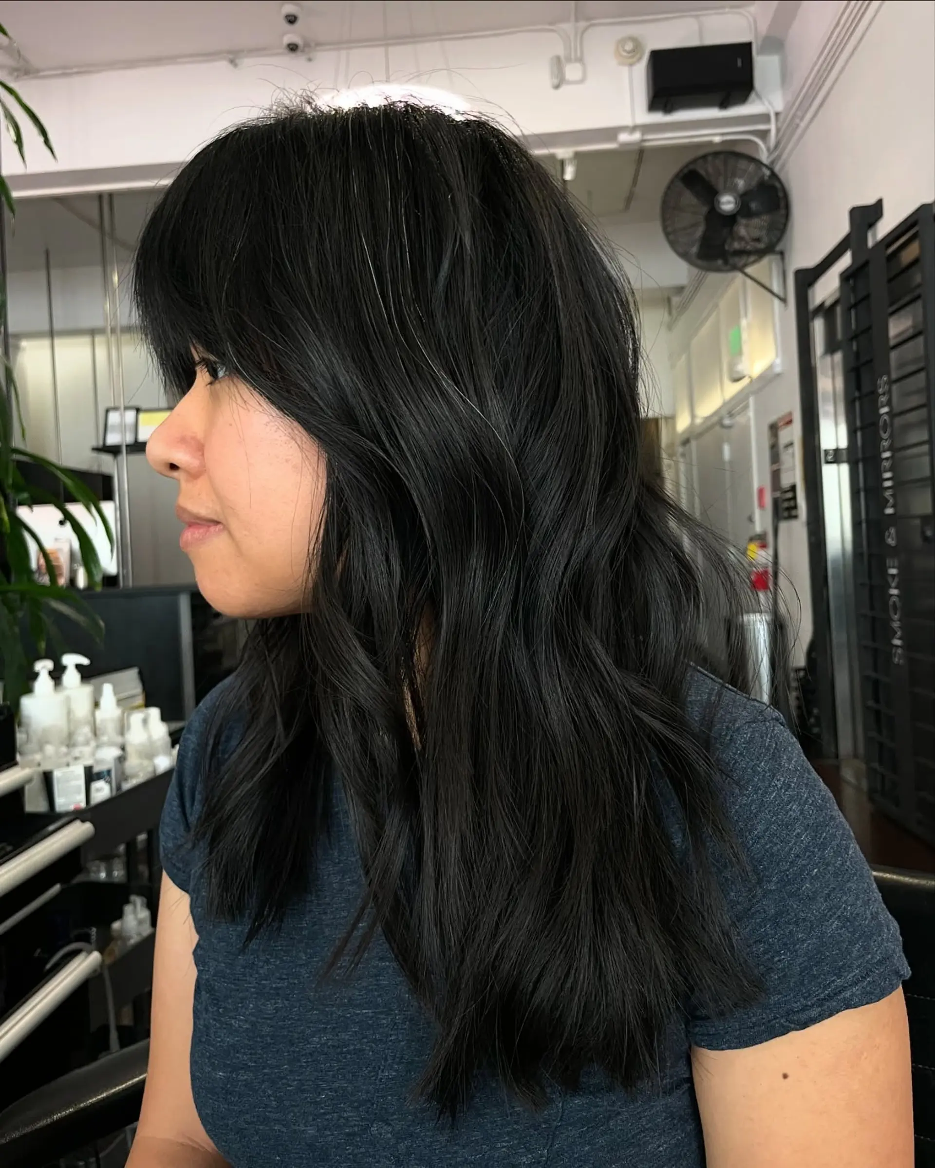 Long black hair styled with subtle waves, soft face-framing layers, and straight-across bangs. 1