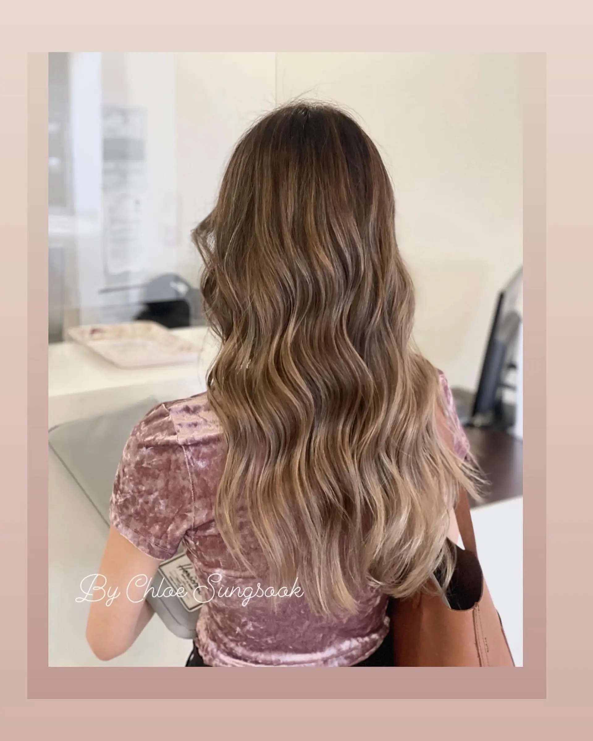 Long hair styled into smooth, defined waves featuring a blended camel brown balayage. 1