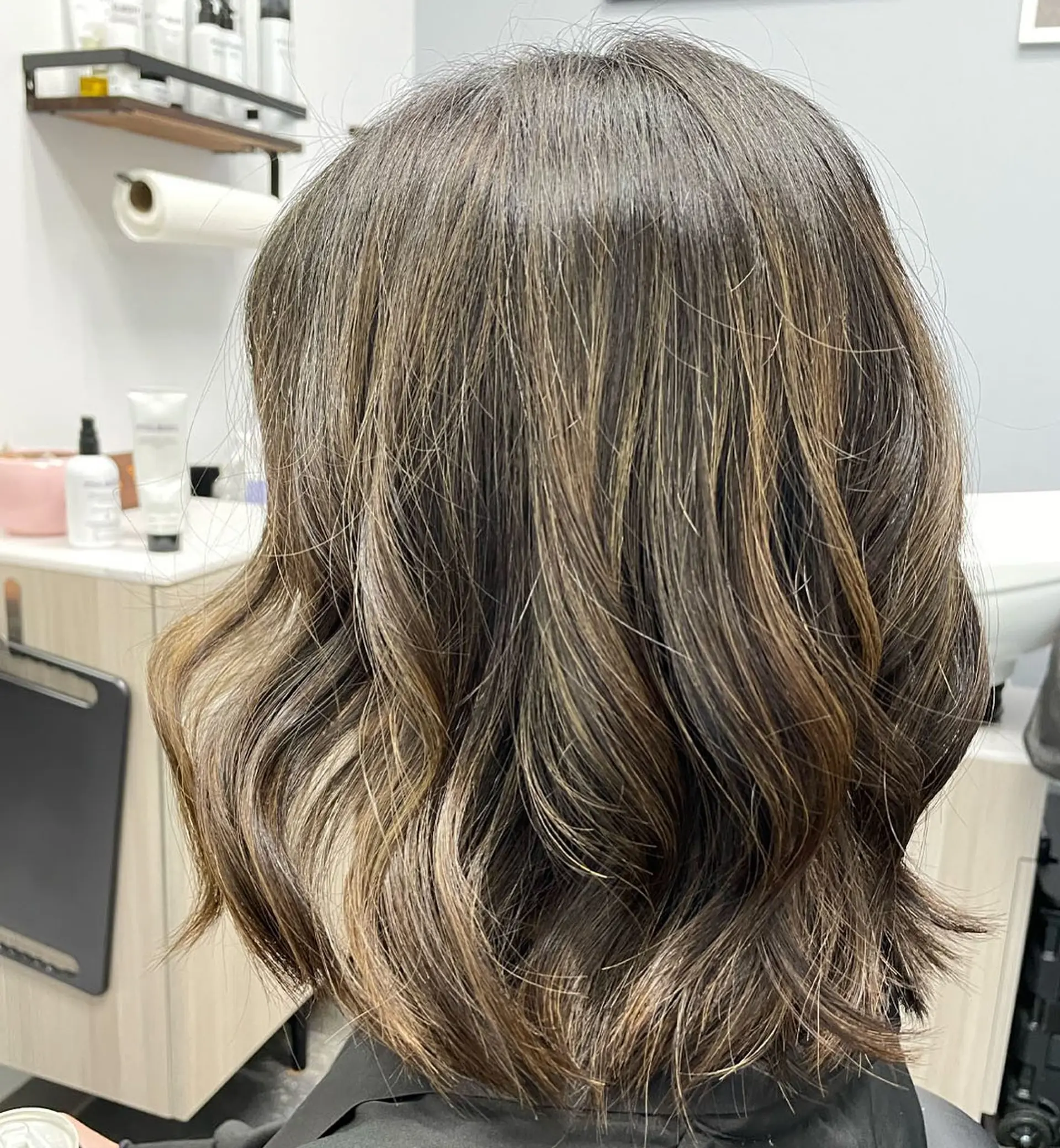 A textured shoulder-length bob styled with soft, undone waves and dimensional balayage highlights. 1