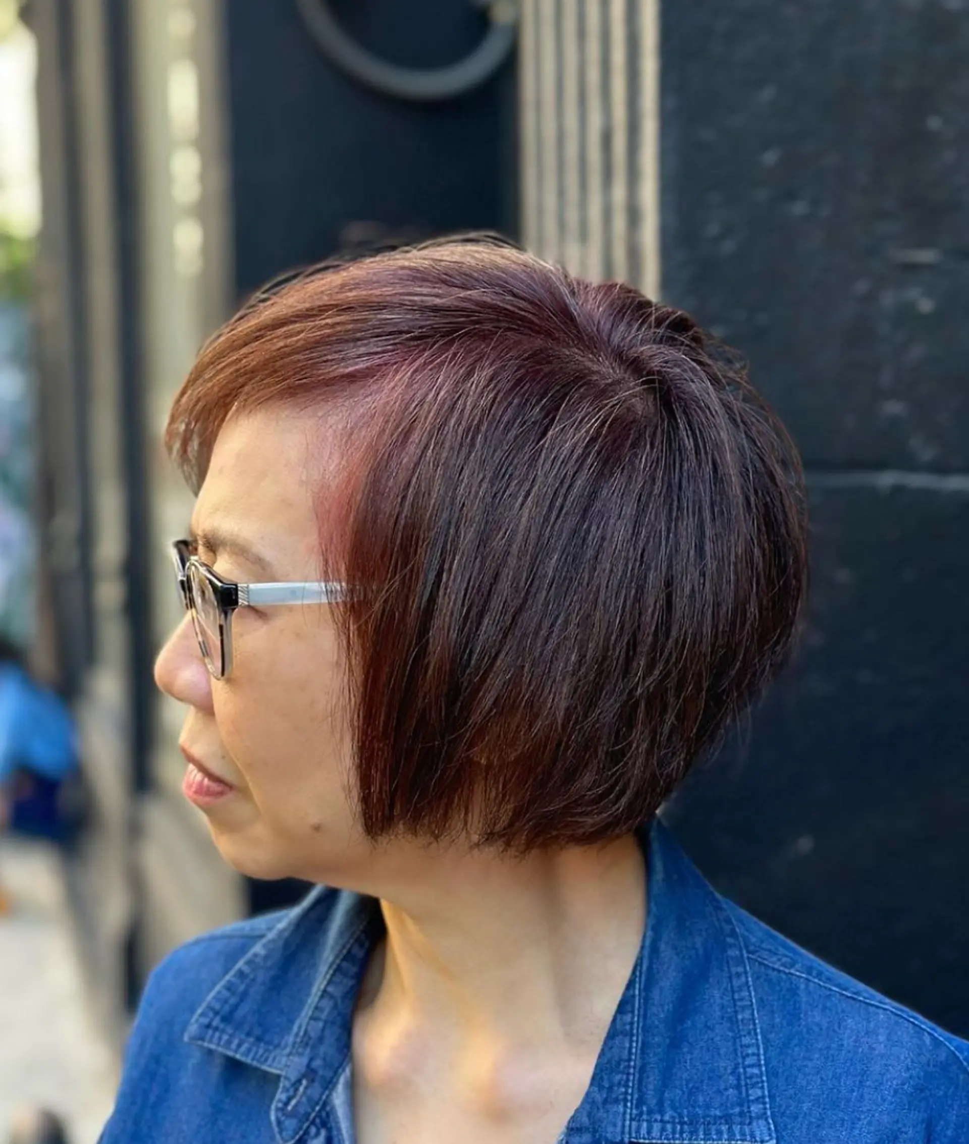 Short, precisely layered dark brown hair with subtle red highlights, side-swept bangs, and a smooth finish. Ideal for a sophisticated, modern look.

Color by @simabeautynyc
 1