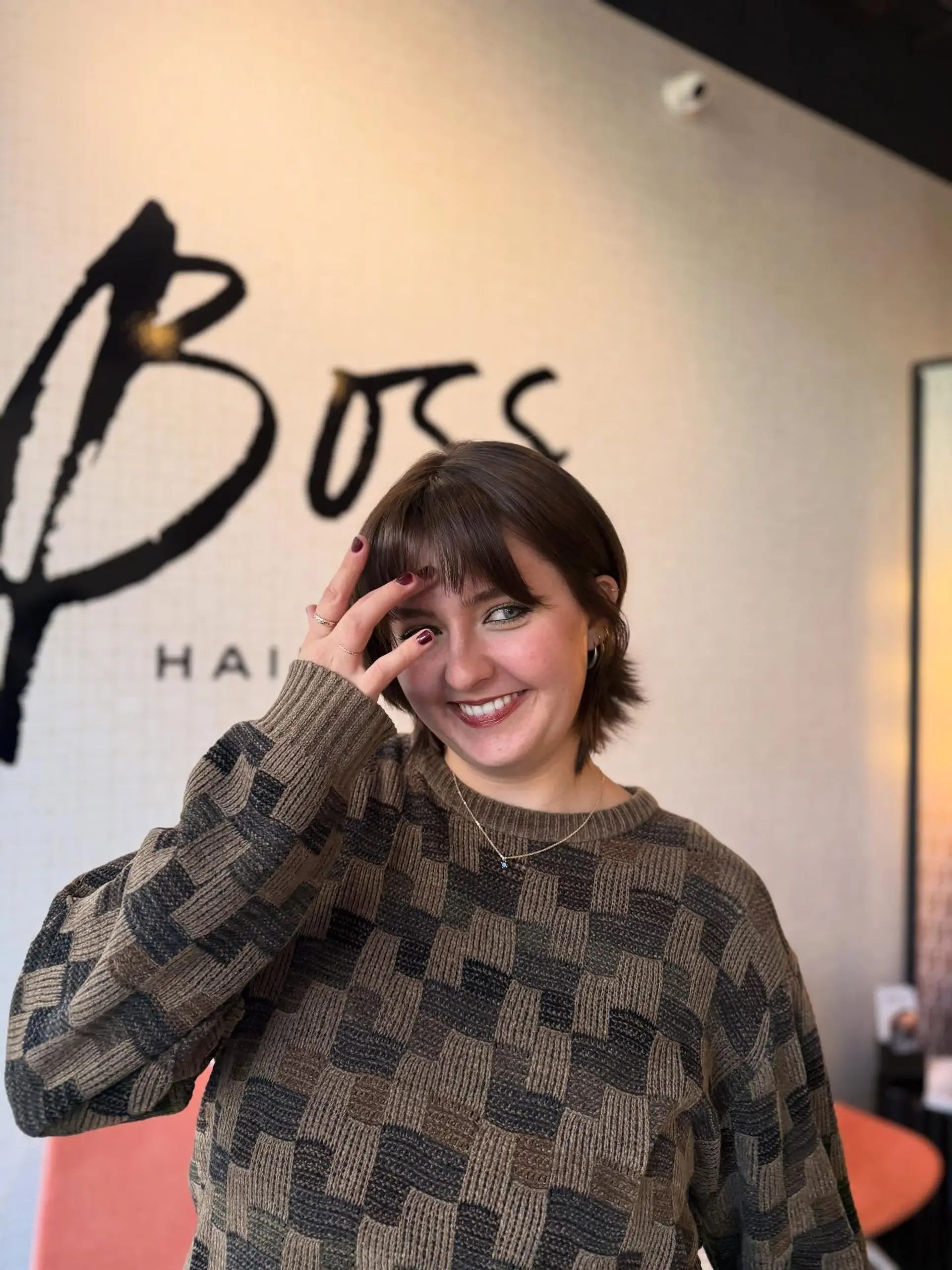 A glossy rich chocolate brown short bob haircut styled with light wispy fringe bangs. 1