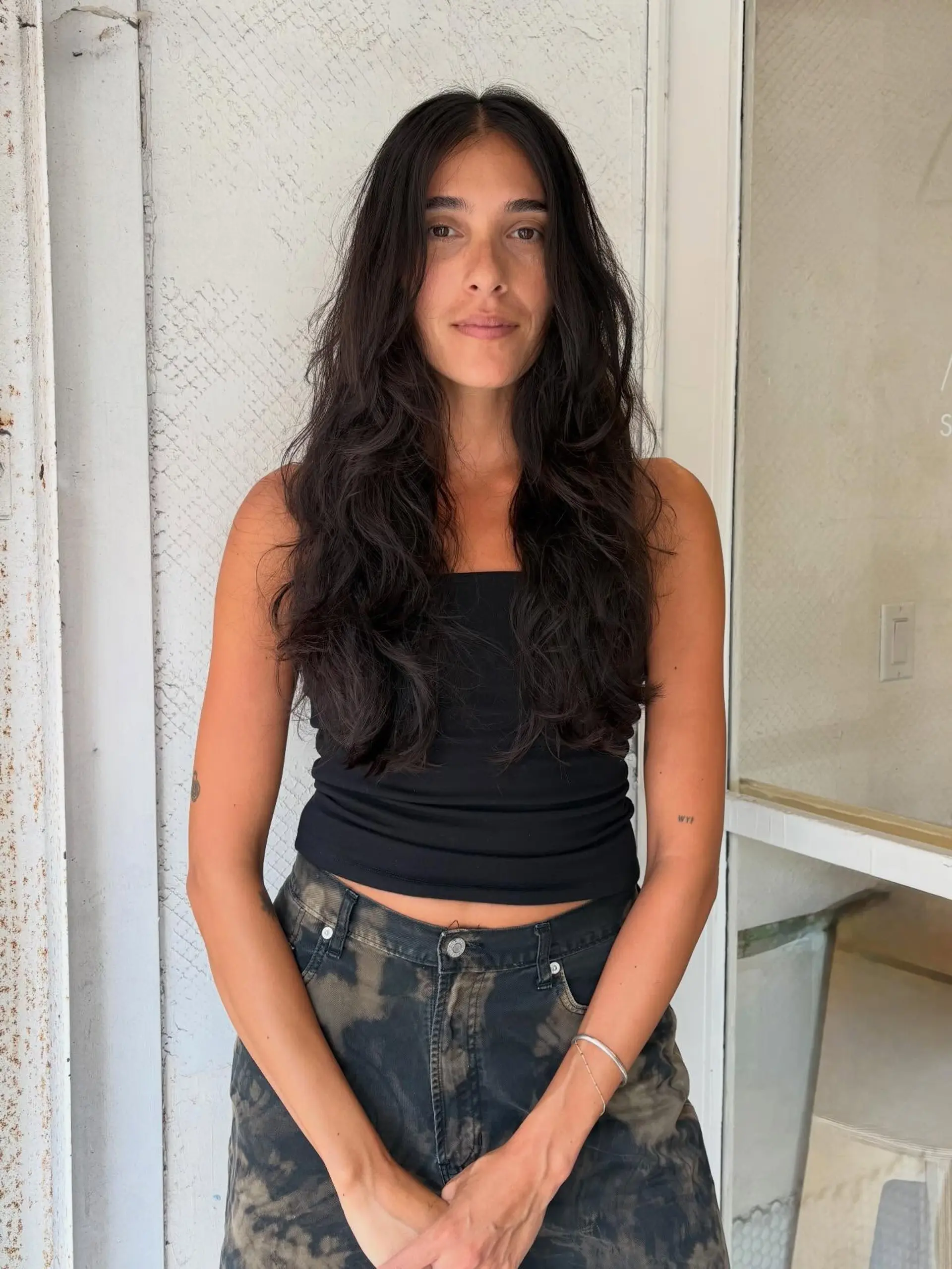 Long, dark brown hair cut with textured layers and styled into natural, effortless waves with a center part. 1