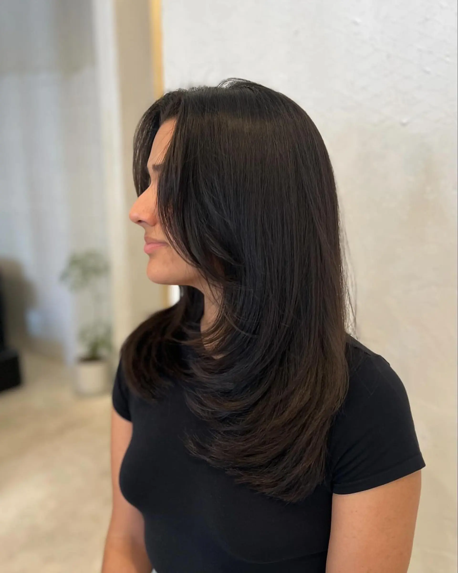 Long, straight black hair with layers. Side part with natural shine and sleek look. 1