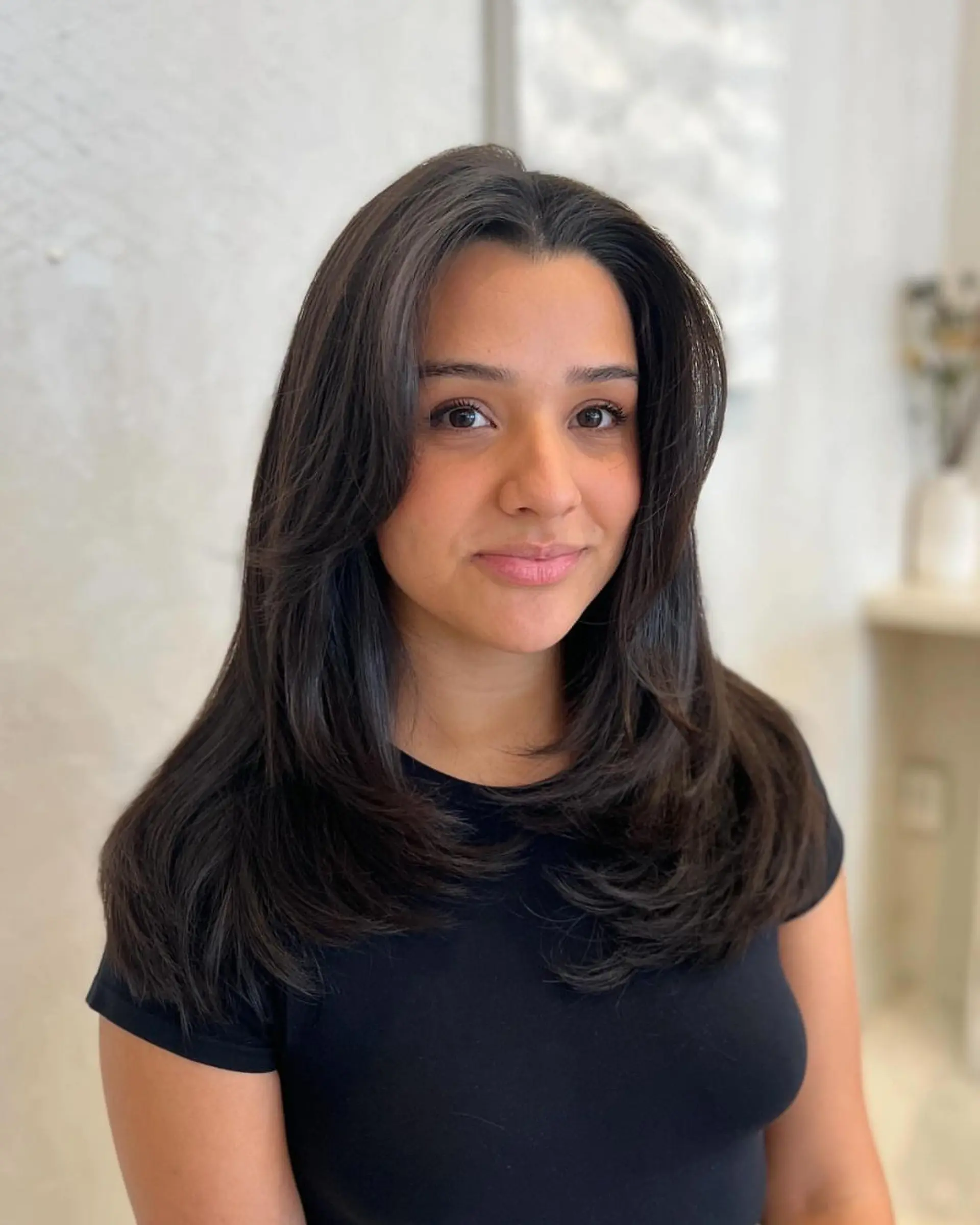 Long, straight black hair with layers. Side part with natural shine and sleek look. 2