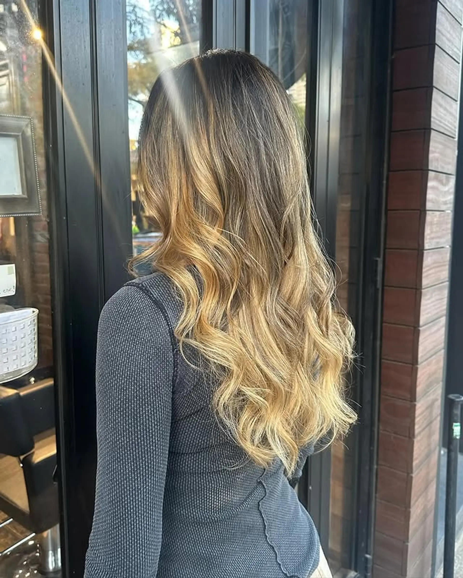 Bronde balayage with soft waves. This style features a seamless blend of brown and blonde tones, creating a sun-kissed effect with gentle, flowing waves. 1