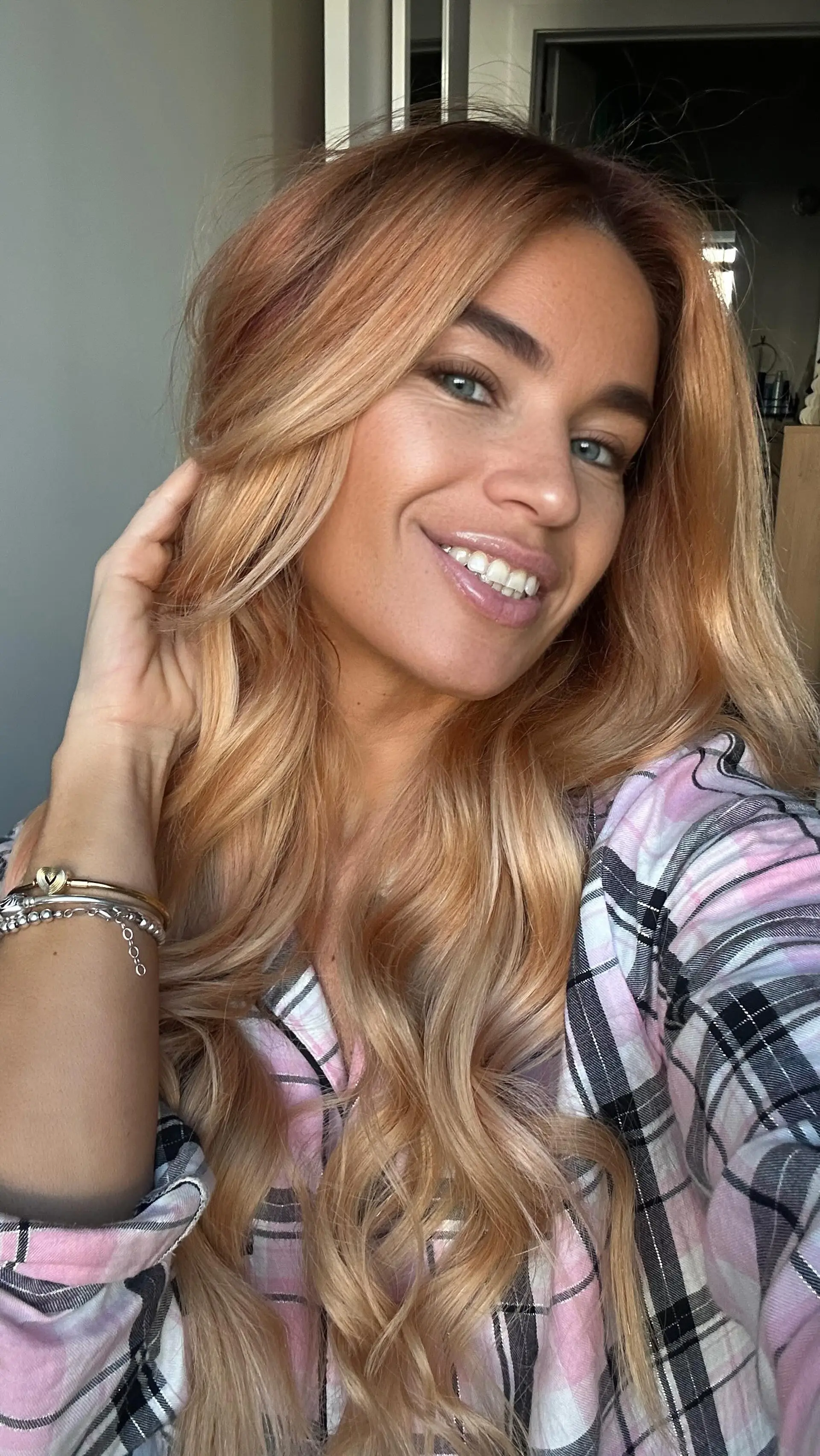 Long strawberry blonde hair styled into soft, voluminous cascading waves with a subtle side part. 1