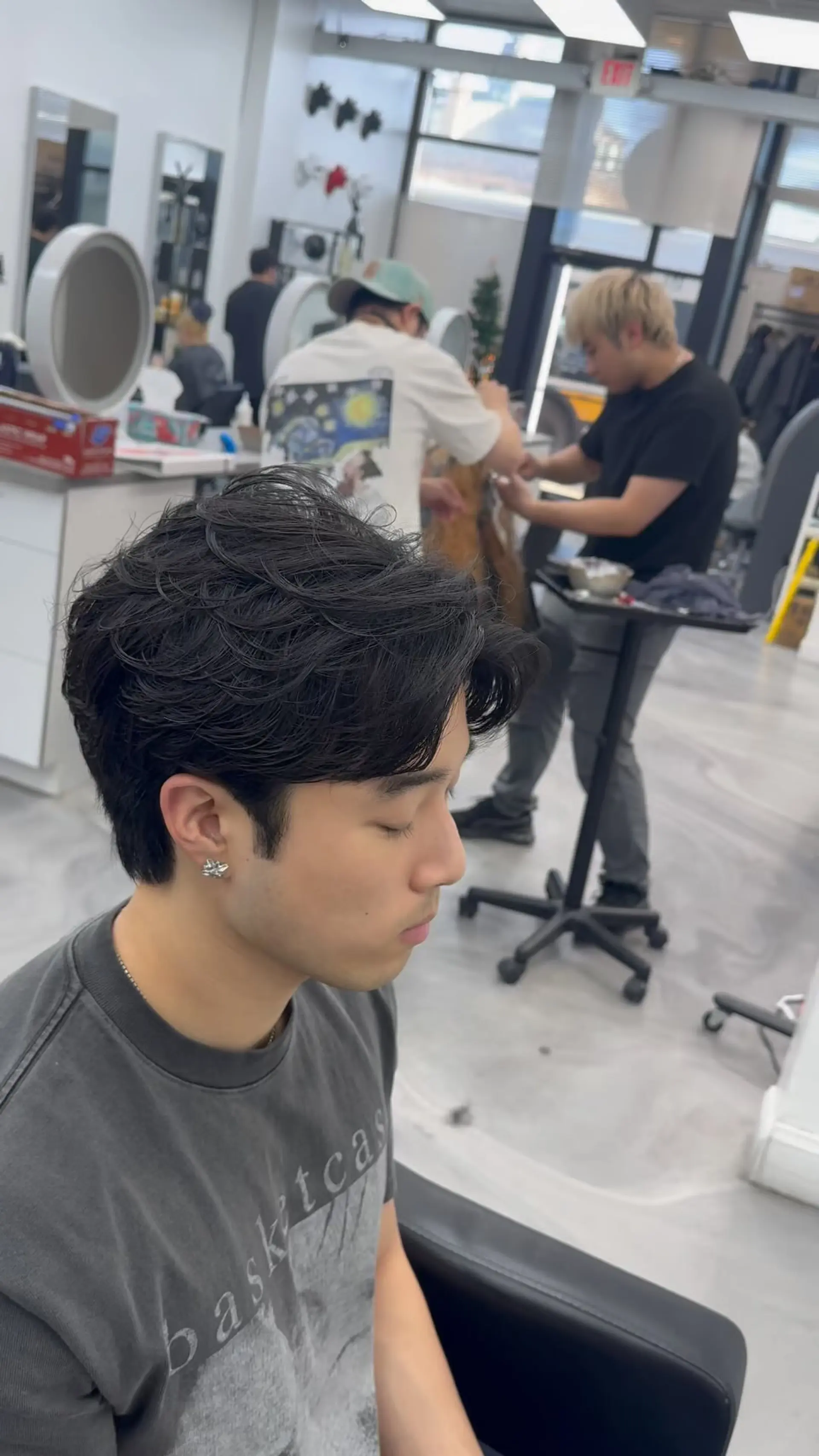 A men's short haircut featuring soft, textured waves and a flowing curtain fringe. 1