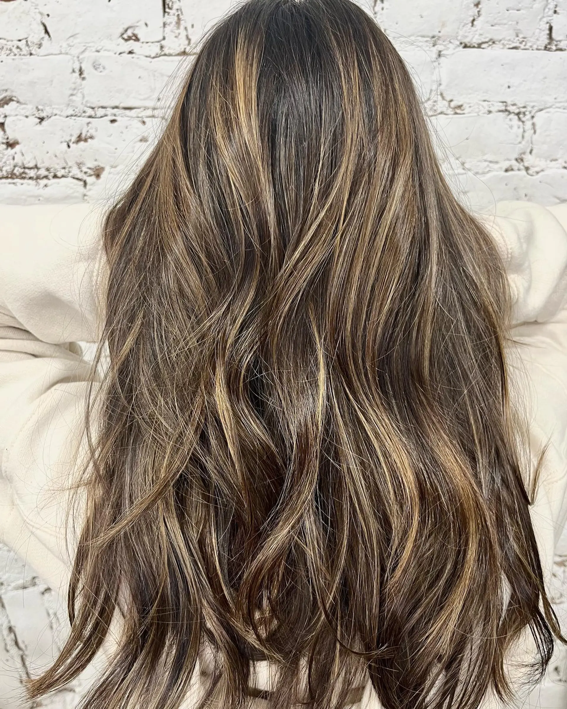 Long layered hair with fine caramel and honey blonde balayage highlights on a dark brown base. 1