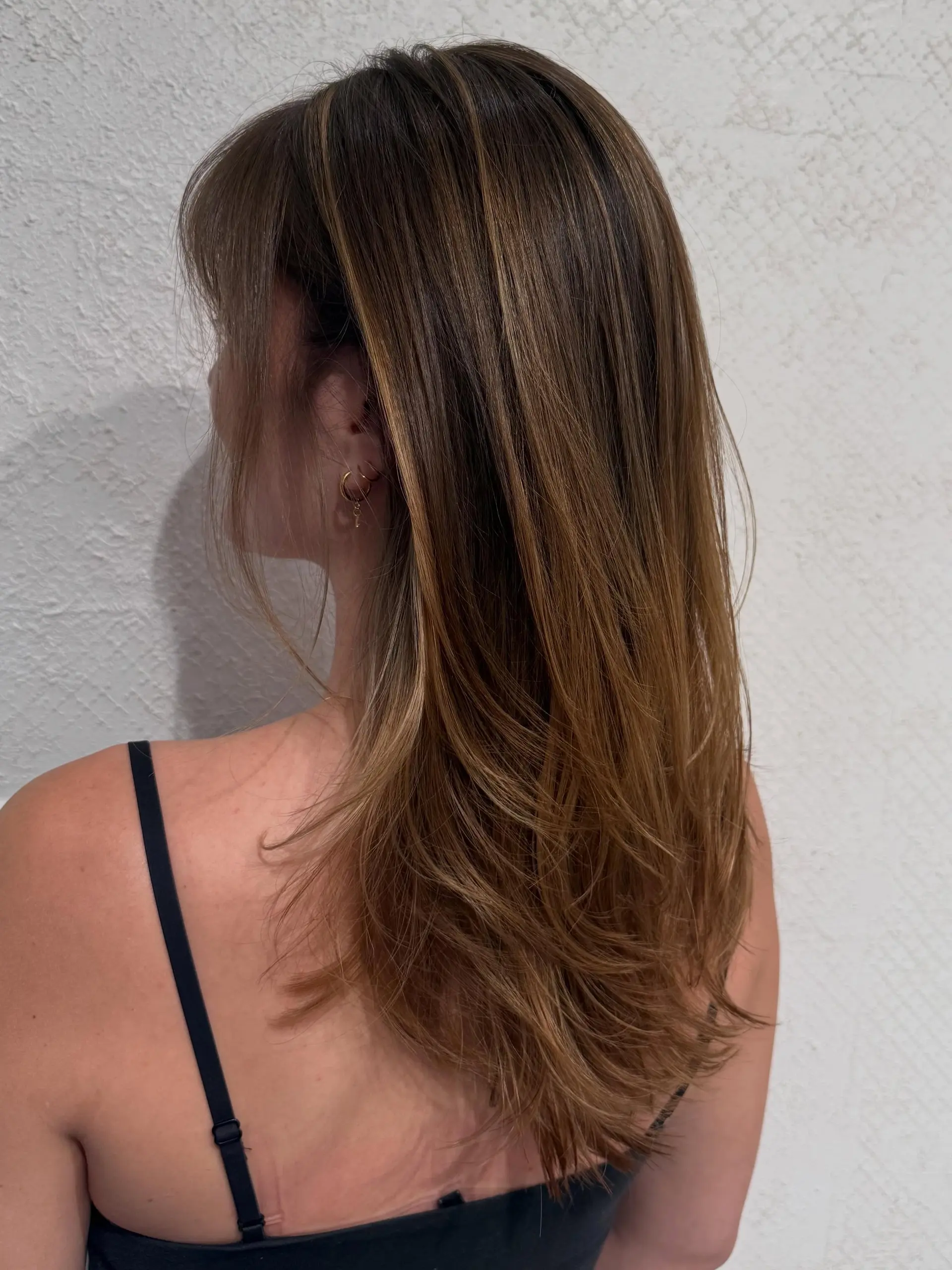 Soft long layers featuring a blended caramel balayage on a natural brunette base. 1