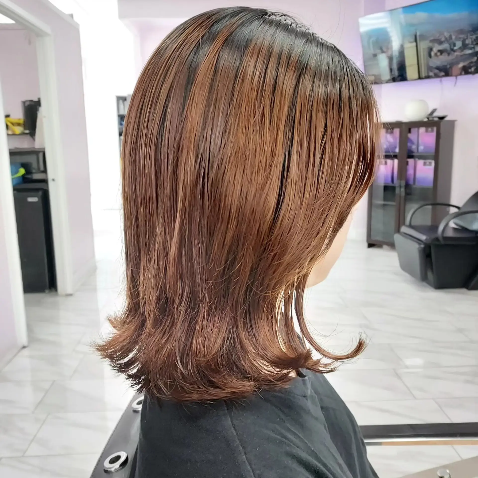 A sleek shoulder-length cut styled straight with playful outward-flipped ends in a warm chestnut brown tone. 1