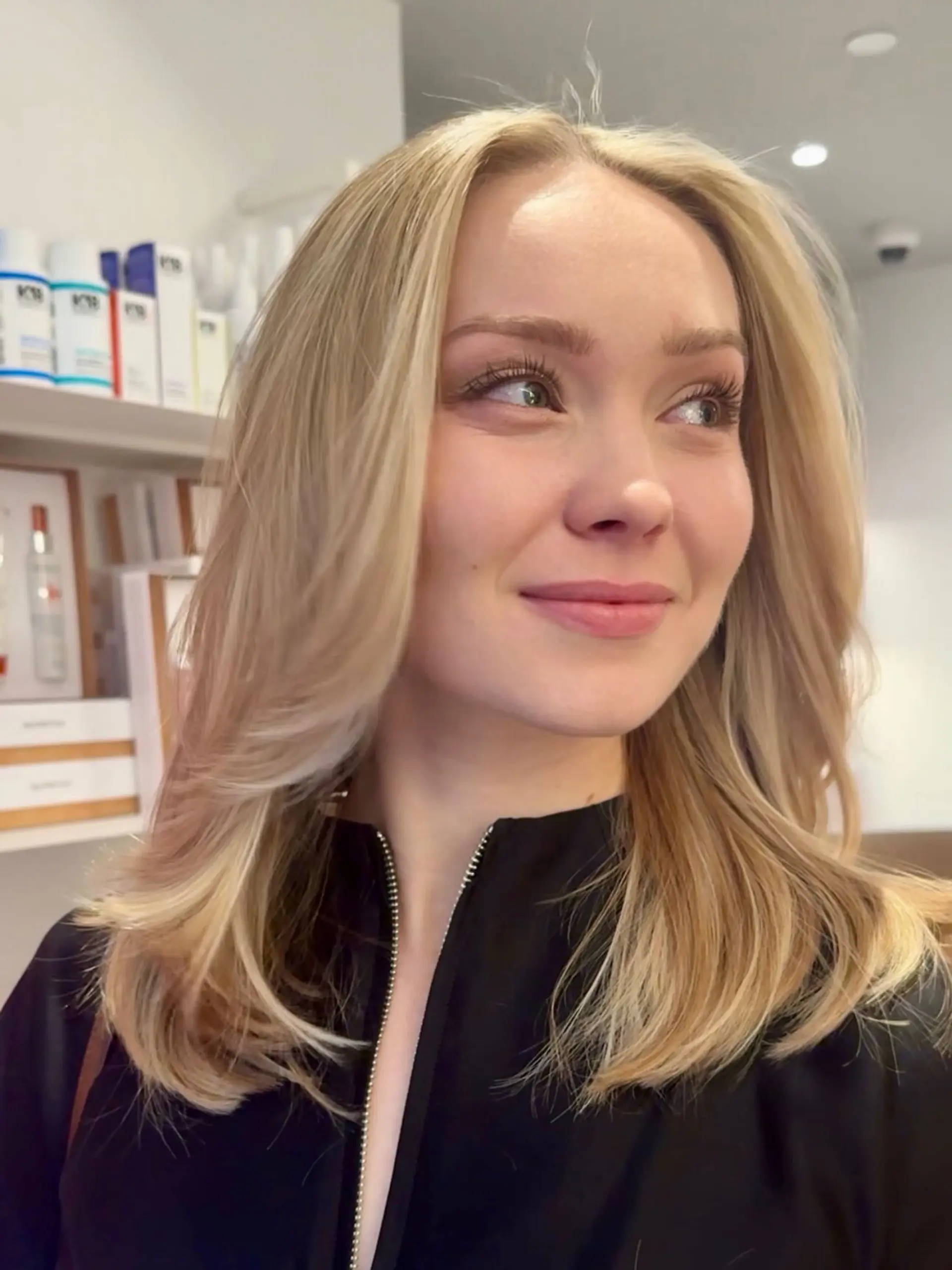 Medium-length bright blonde hair featuring feathered face-framing layers and styled with a voluminous, soft blowout. 1
