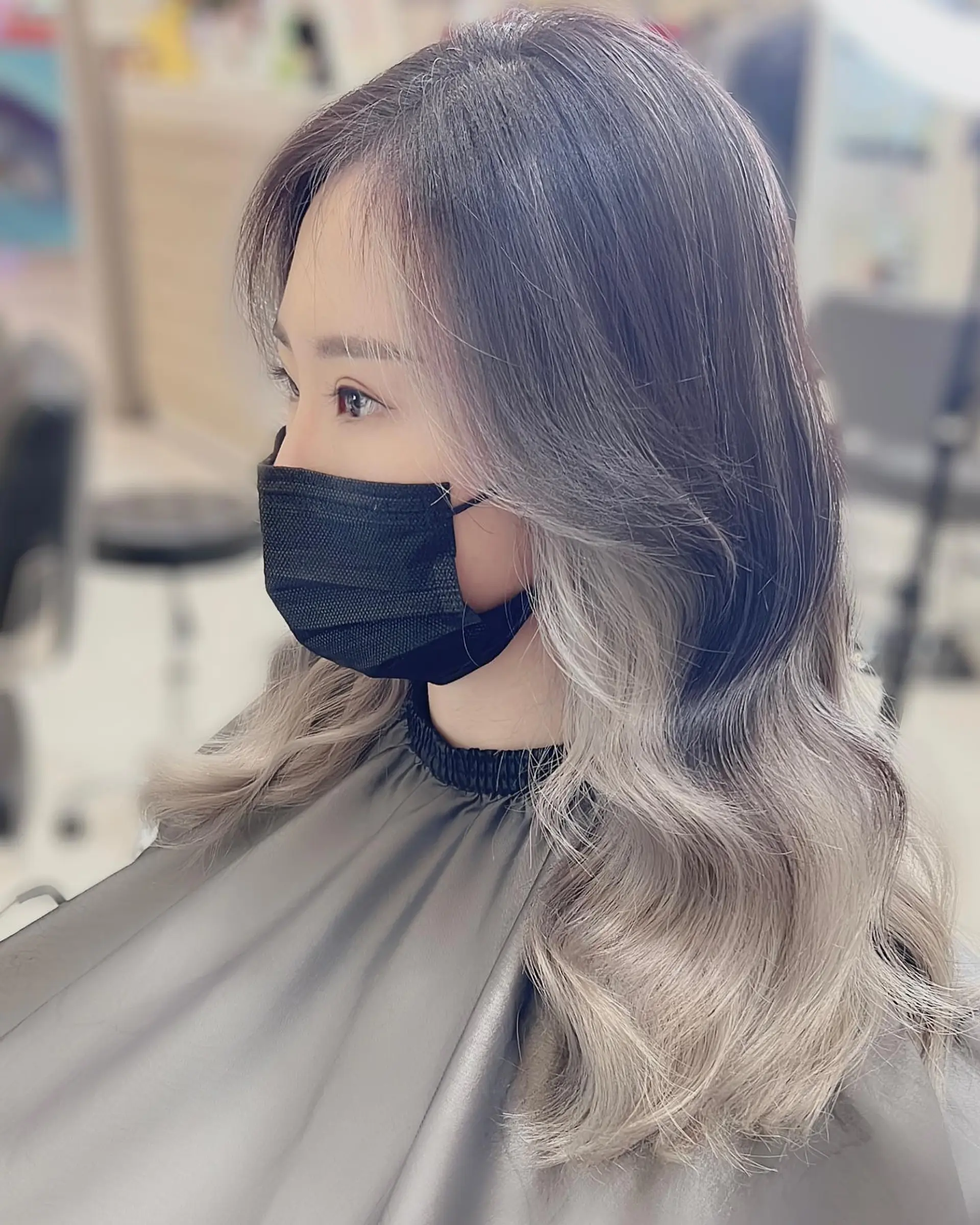 A wavy medium-length hairstyle featuring a shadow root, ash blonde balayage, and a prominent money piece. 1