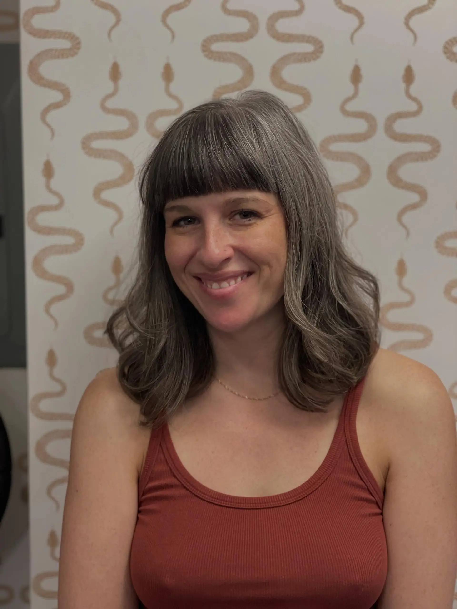 Medium-length haircut with blunt precision bangs and soft, voluminous movement through the wavy ends. 1