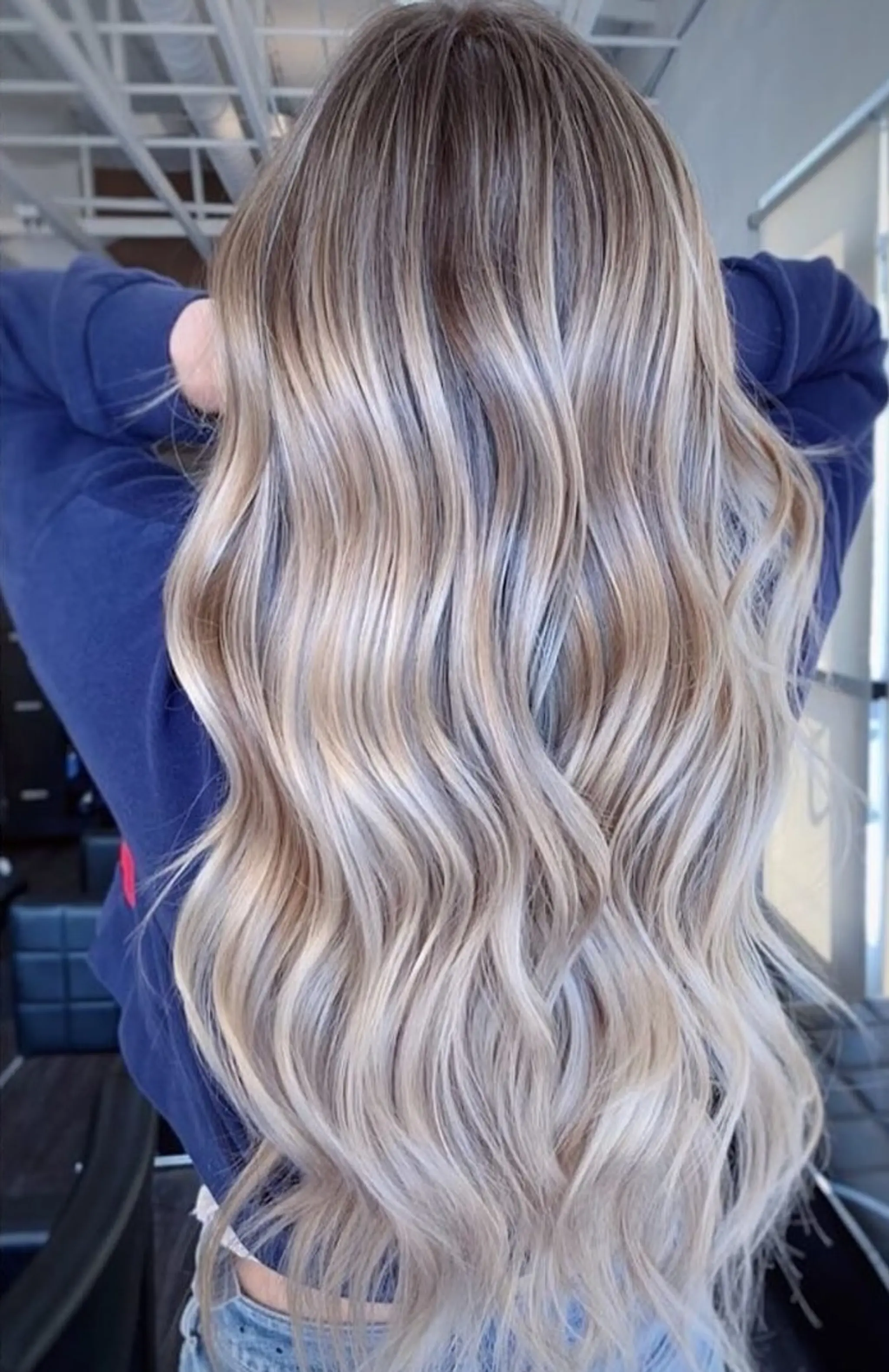 Very long, naturally wavy hair with a sun-kissed blend of blonde hues including ash blonde and golden blonde. The soft waves and balayage effect add an elegant, beachy charm. Toner: 8V, 8P, 10A - Equal Parts w/10 vol