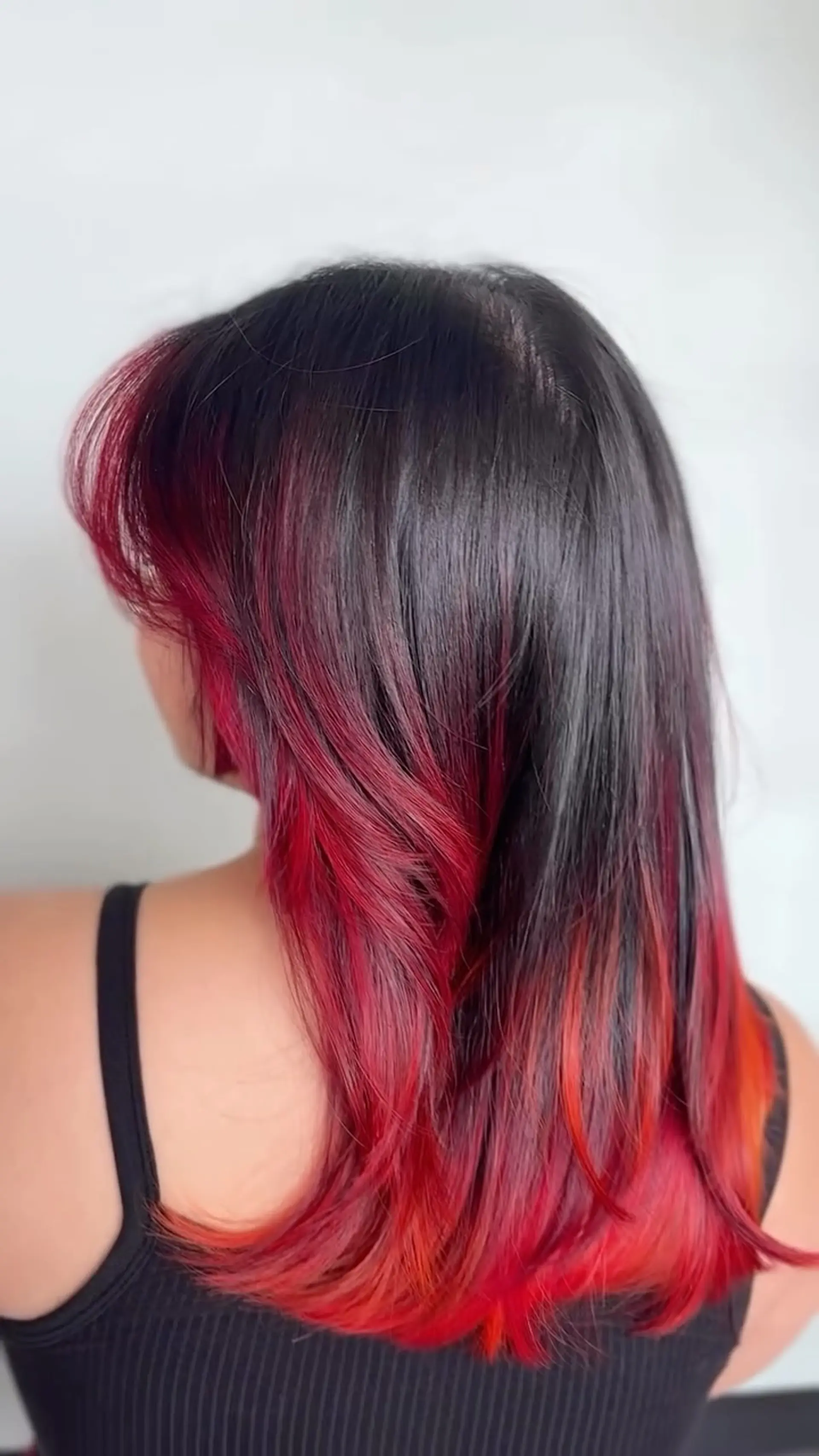 Medium-length dark hair with vibrant flame-red peekaboo underlights and soft layered styling. 1
