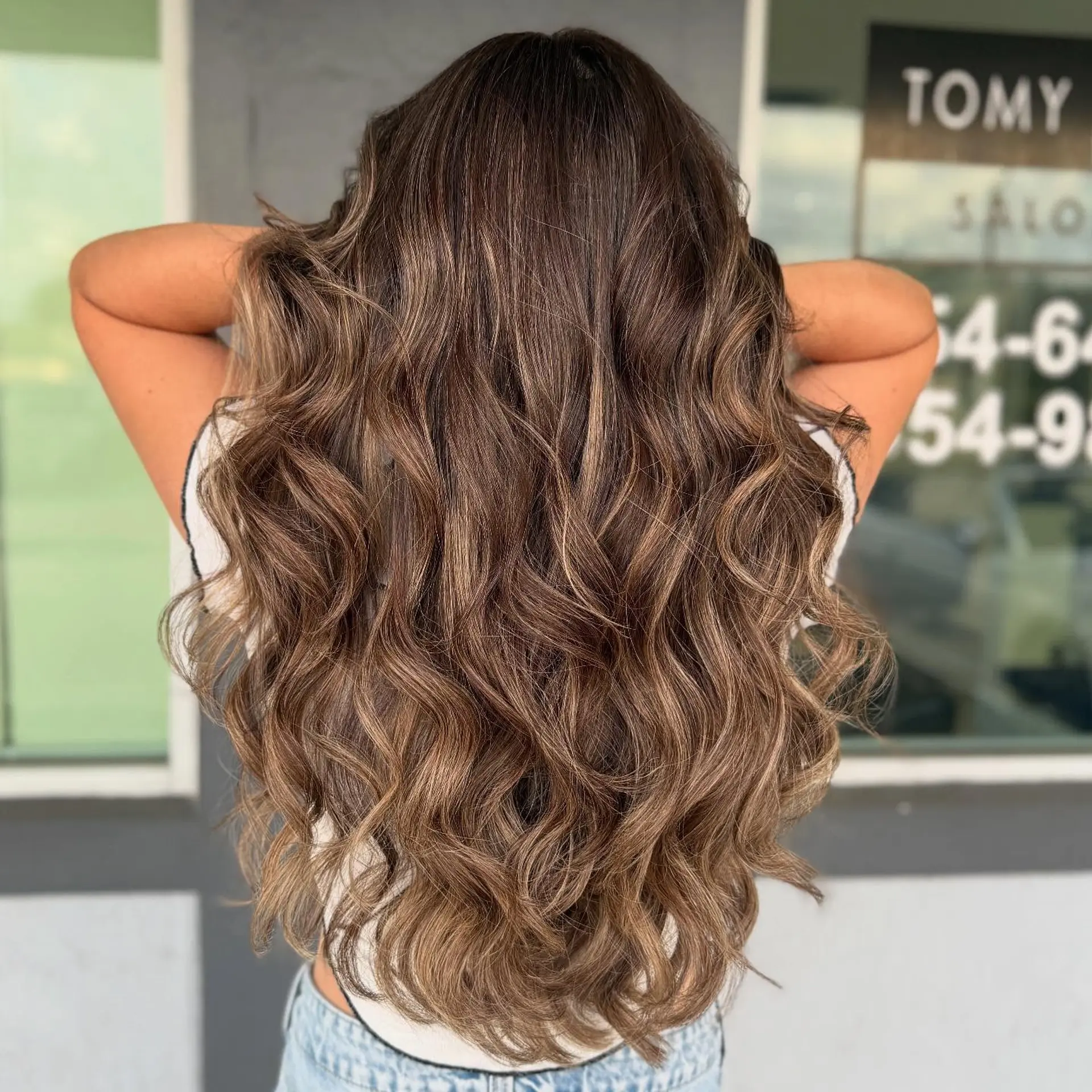 Very long wavy hair with a bronzed balayage, creating a dimensional and goddess-like look. 1