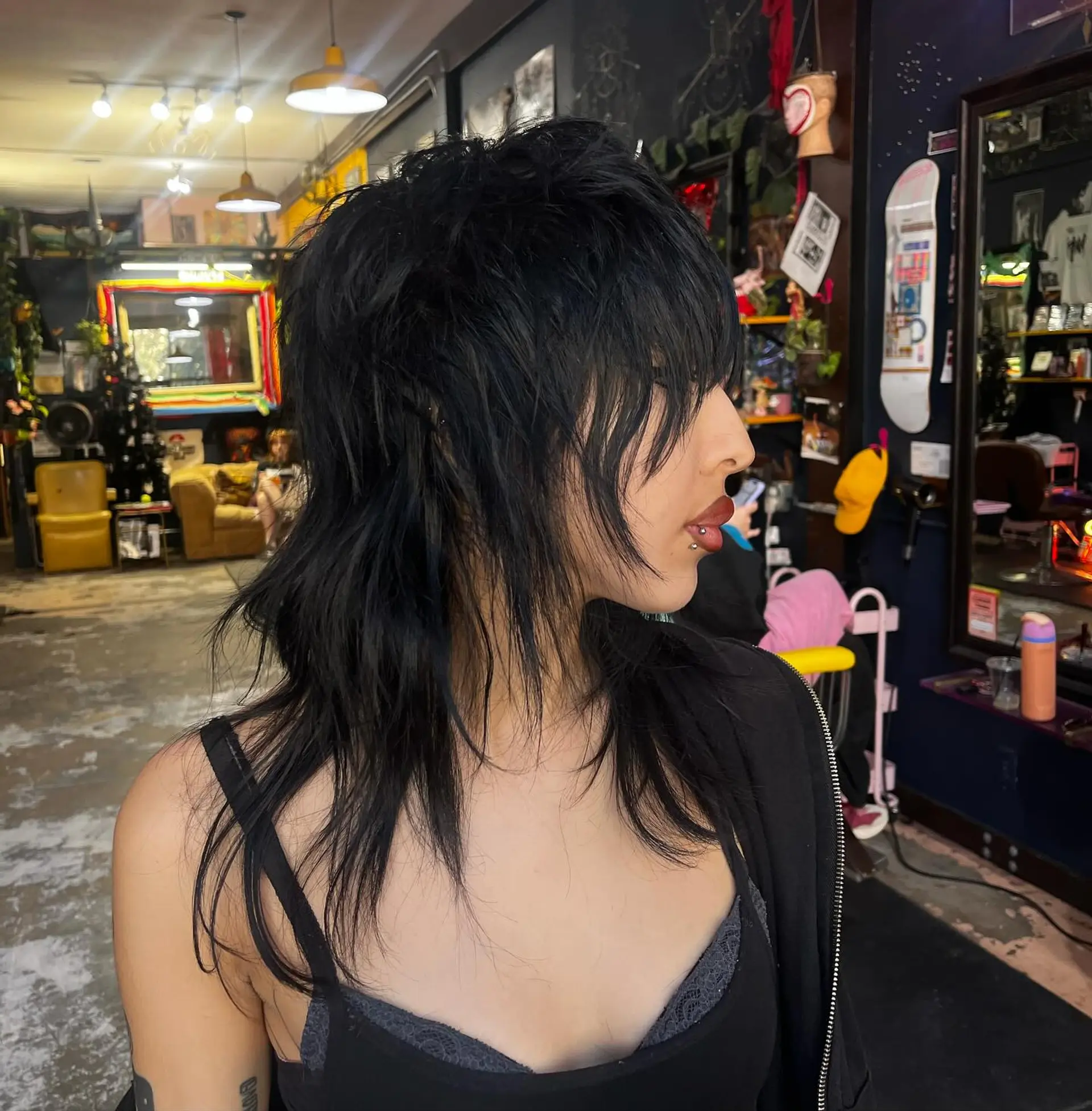 A heavily textured, choppy jet-black wolf cut with piecey face-framing layers and fringe. 1