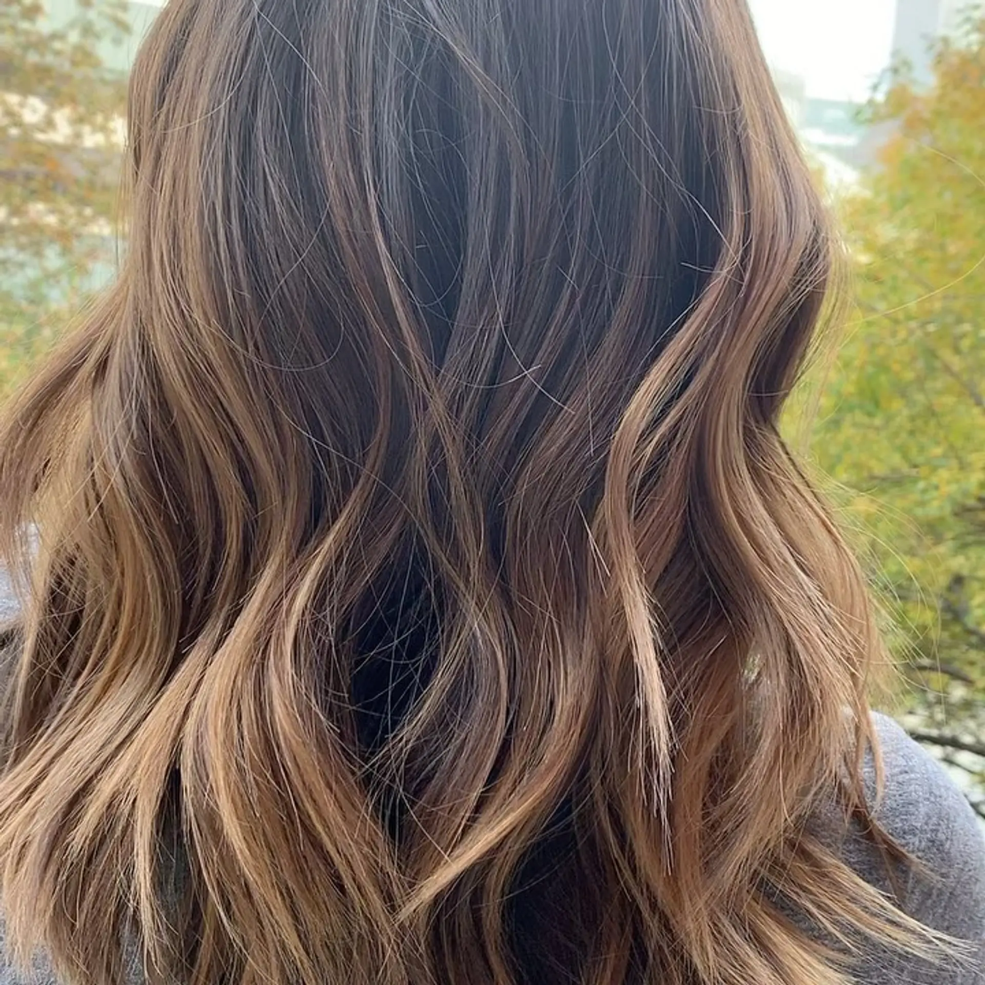 Medium-length textured lob with loose dimensional waves and warm caramel highlights. 1