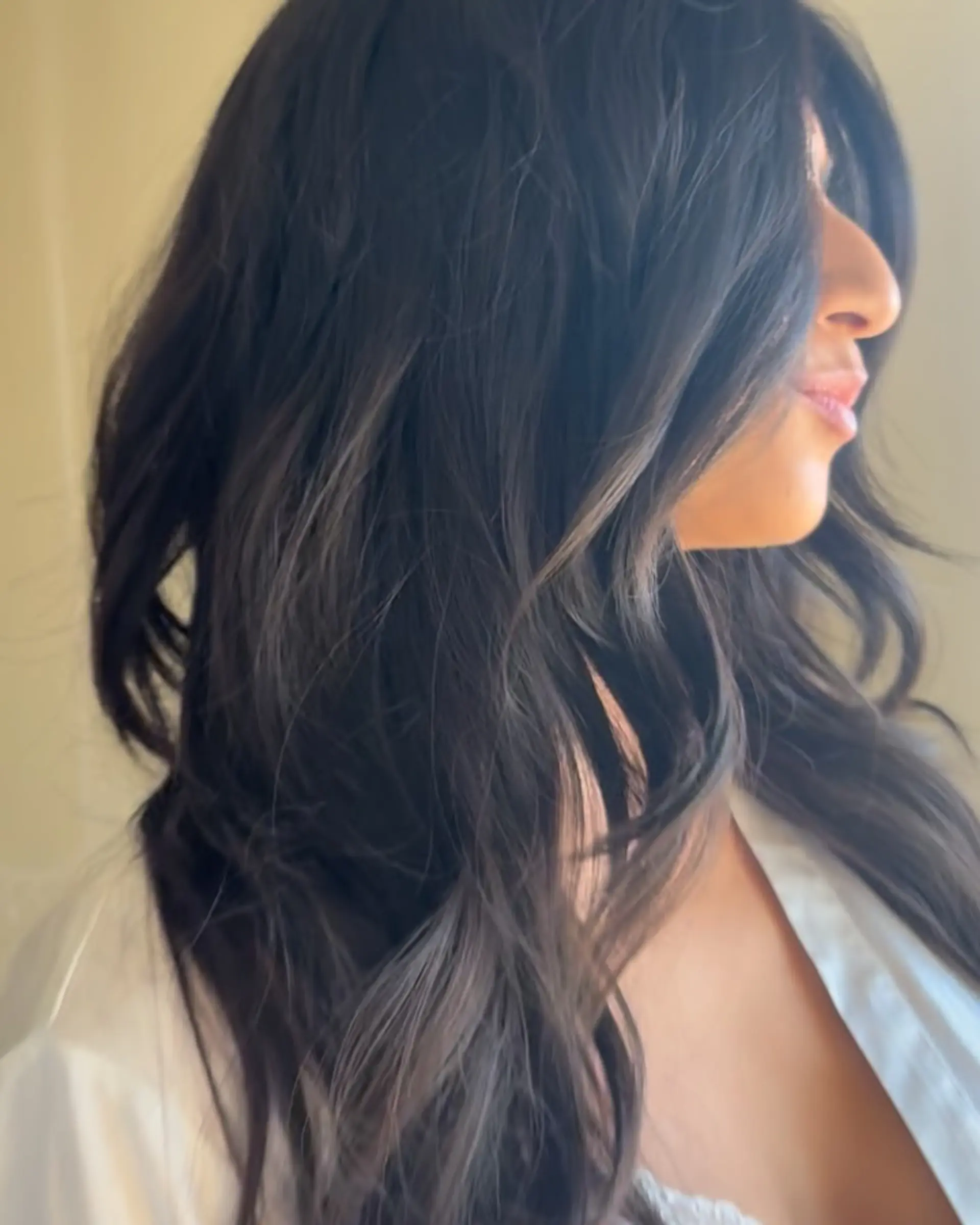 Long espresso hair styled in soft, cascading waves with face-framing layers. 1