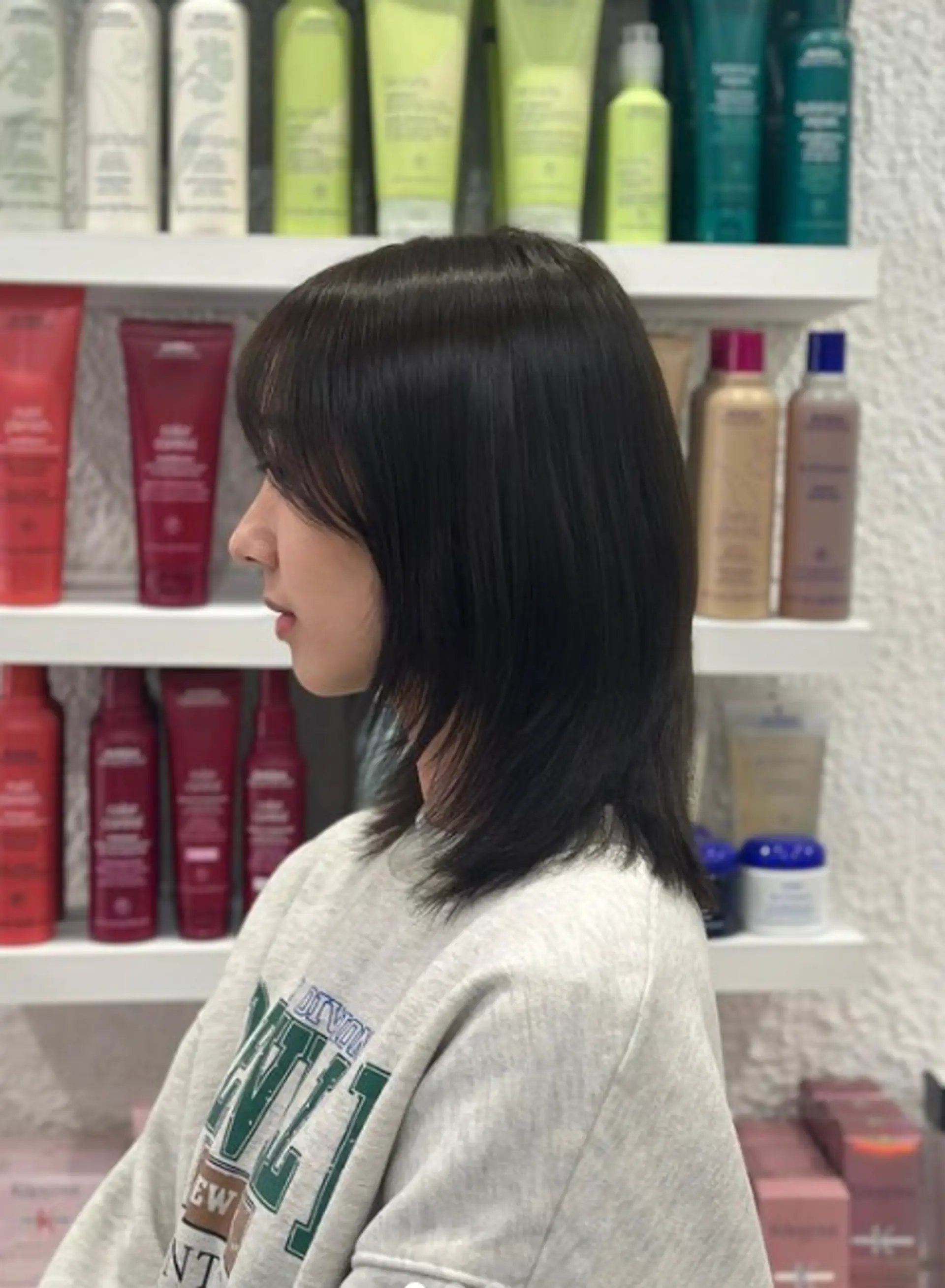 This hairstyle features a modern, sleek bob with medium length, reaching slightly past the shoulders. The hair is straight and has a smooth texture. The style includes side bangs that subtly frame the face, blending seamlessly into the rest of the hair with blunt ends for a refined finish. 1