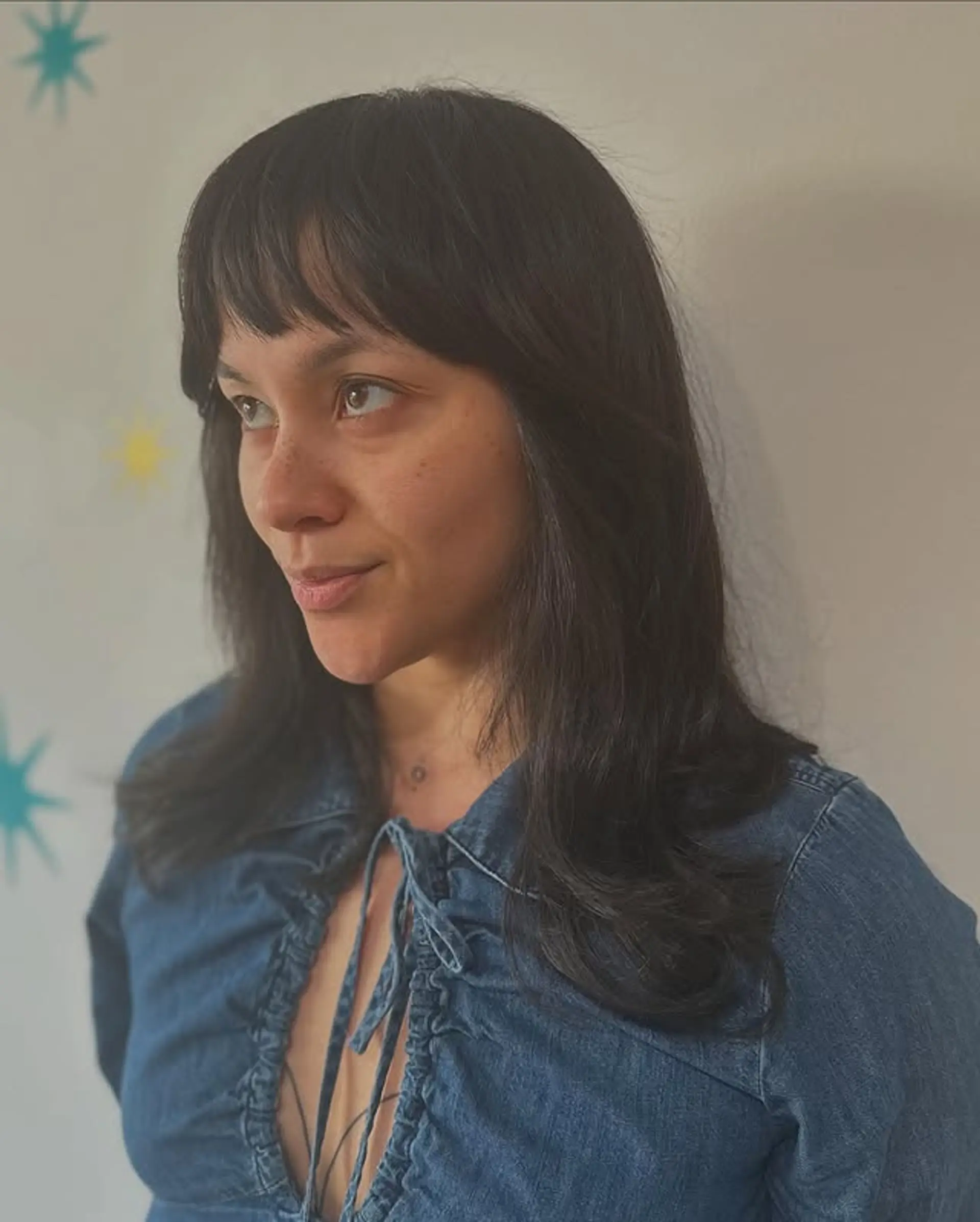 The hairstyle features face-framing layers with curtain bangs. 1