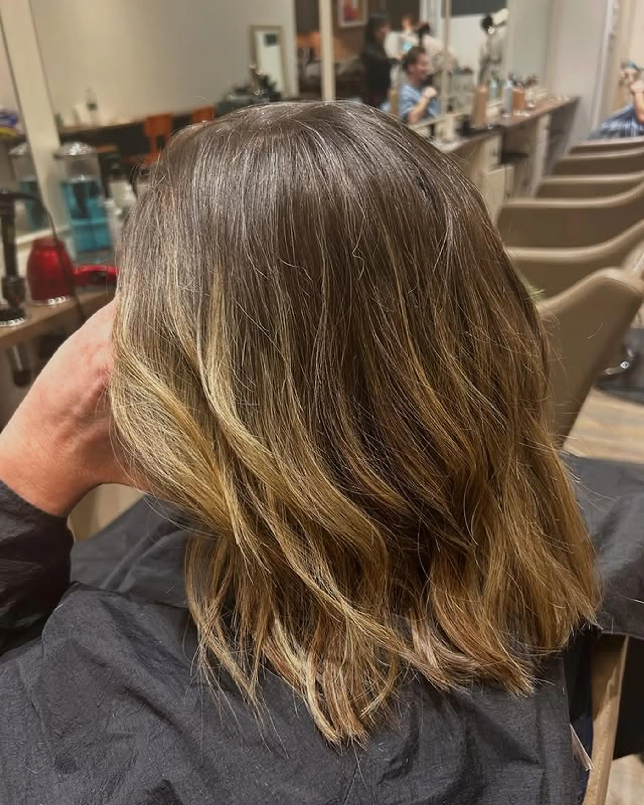 A medium-length lob with a bronde balayage color technique, featuring subtle waves for an effortless look.