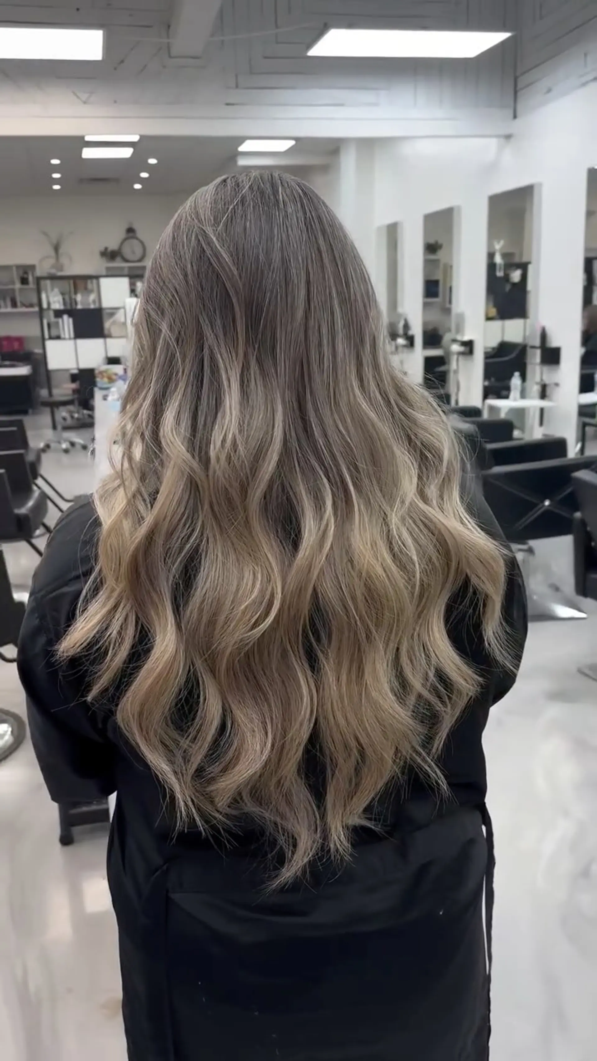Long ash blonde balayage styled with soft, cascading loose waves in a subtle V-cut shape. 1