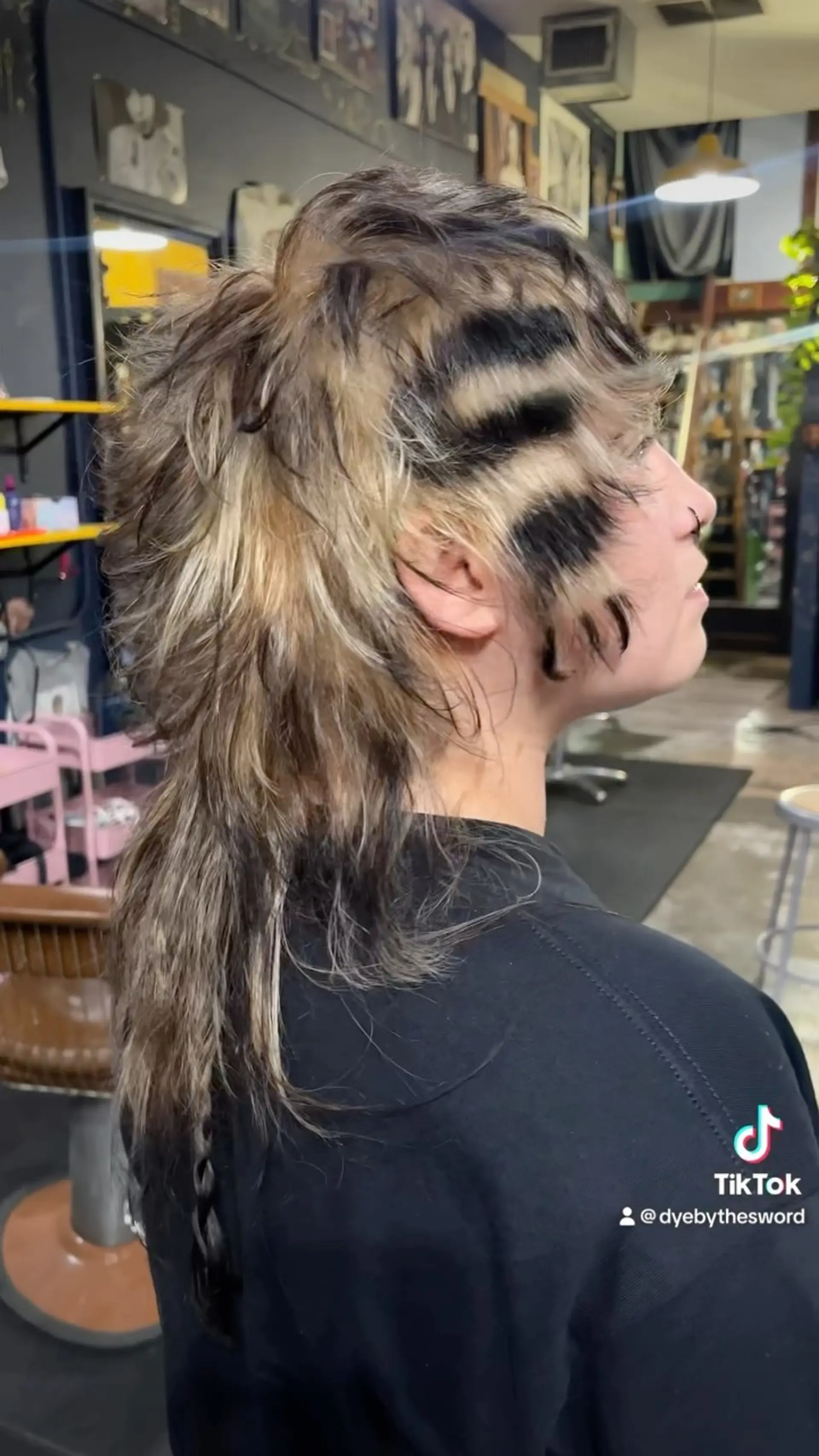 A textured shaggy mullet featuring multi-tonal blonde and brunette layers with horizontal black hand-painted stripes. 1