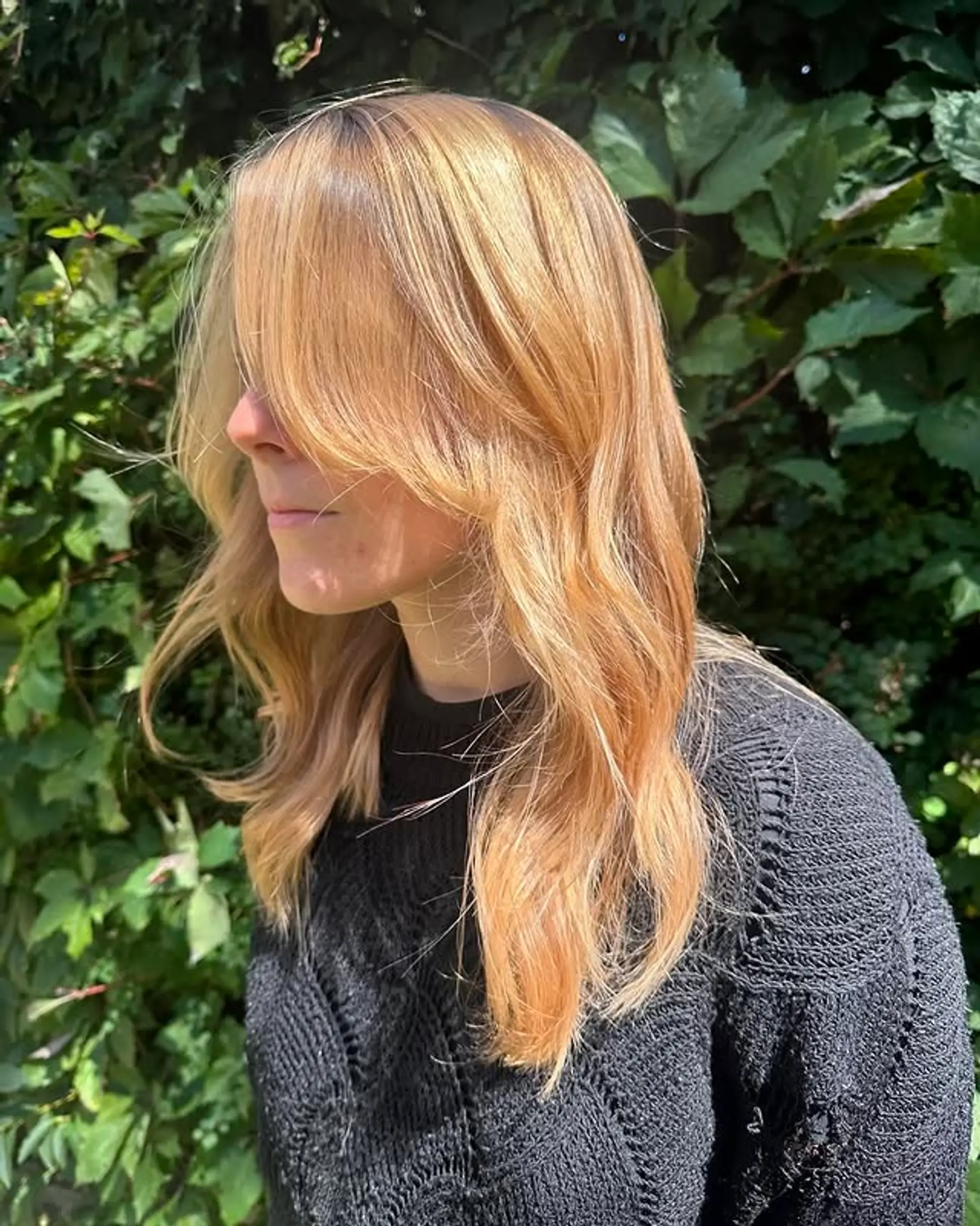 A layered medium hairstyle with loose beachy waves and curtain bangs. 1