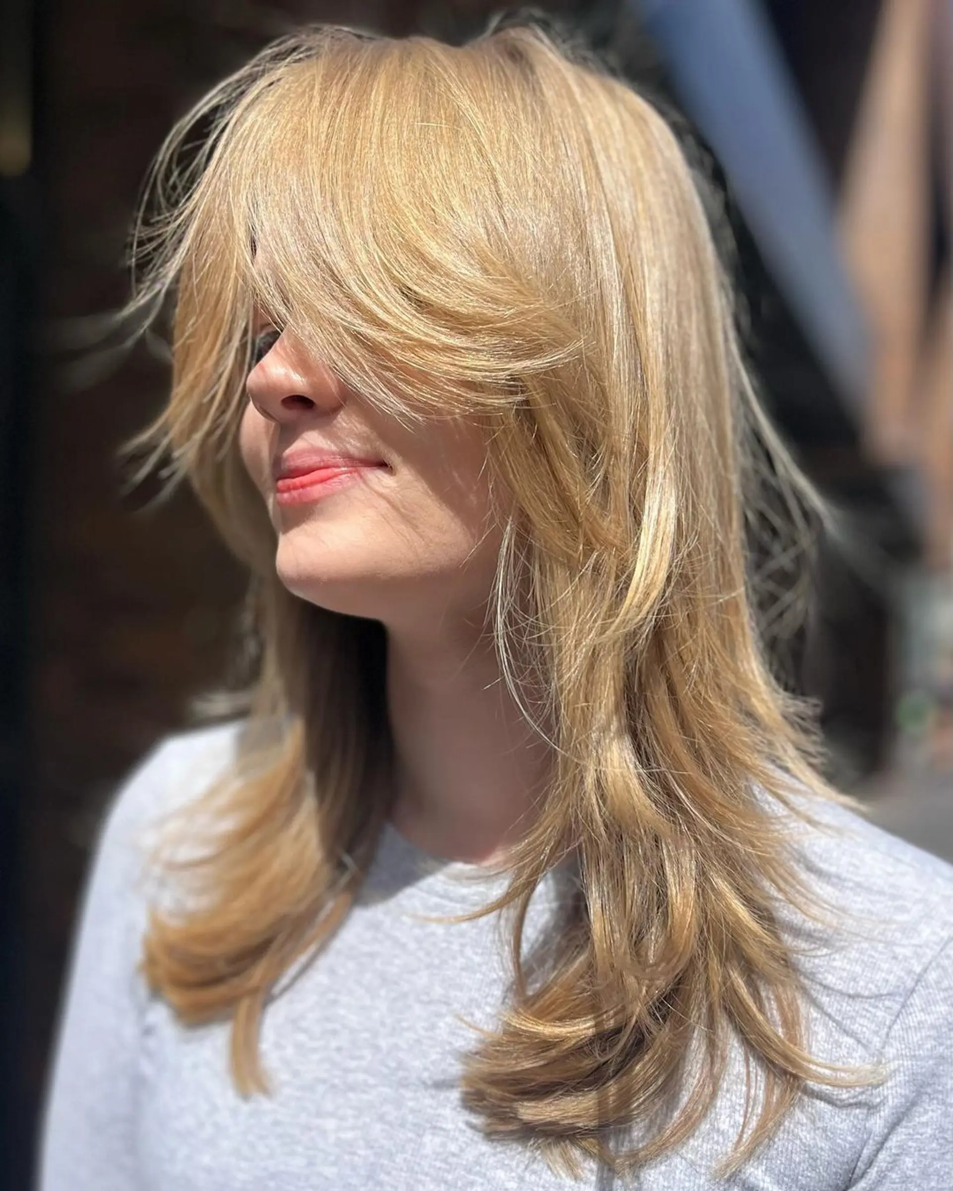 Medium-length, straight, blonde hair with layered, feathered ends and side bangs that blend into the style. 2