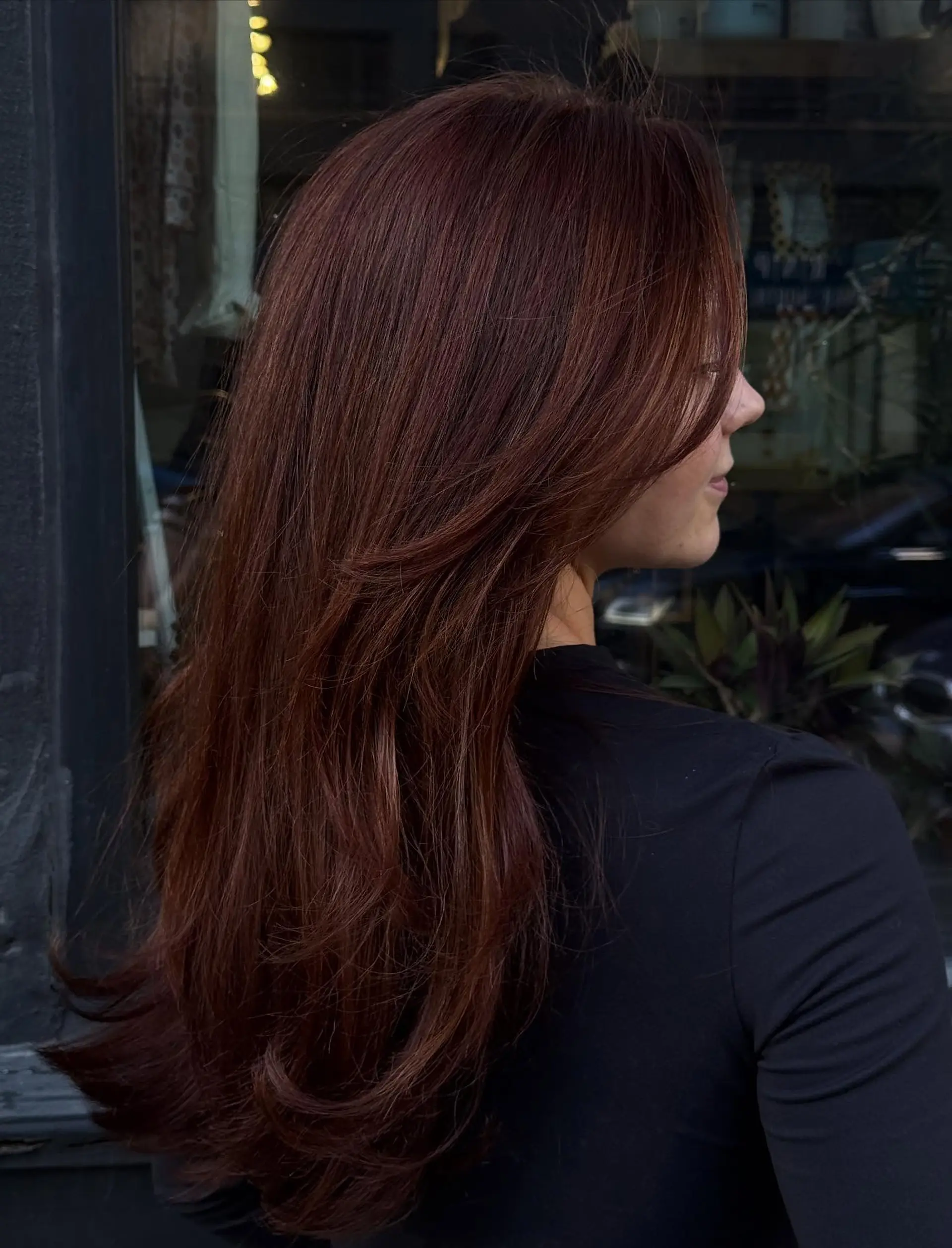Long, lustrous rich copper hair cut with soft, cascading layers and curved face-framing sections styled in a smooth blowout. 1