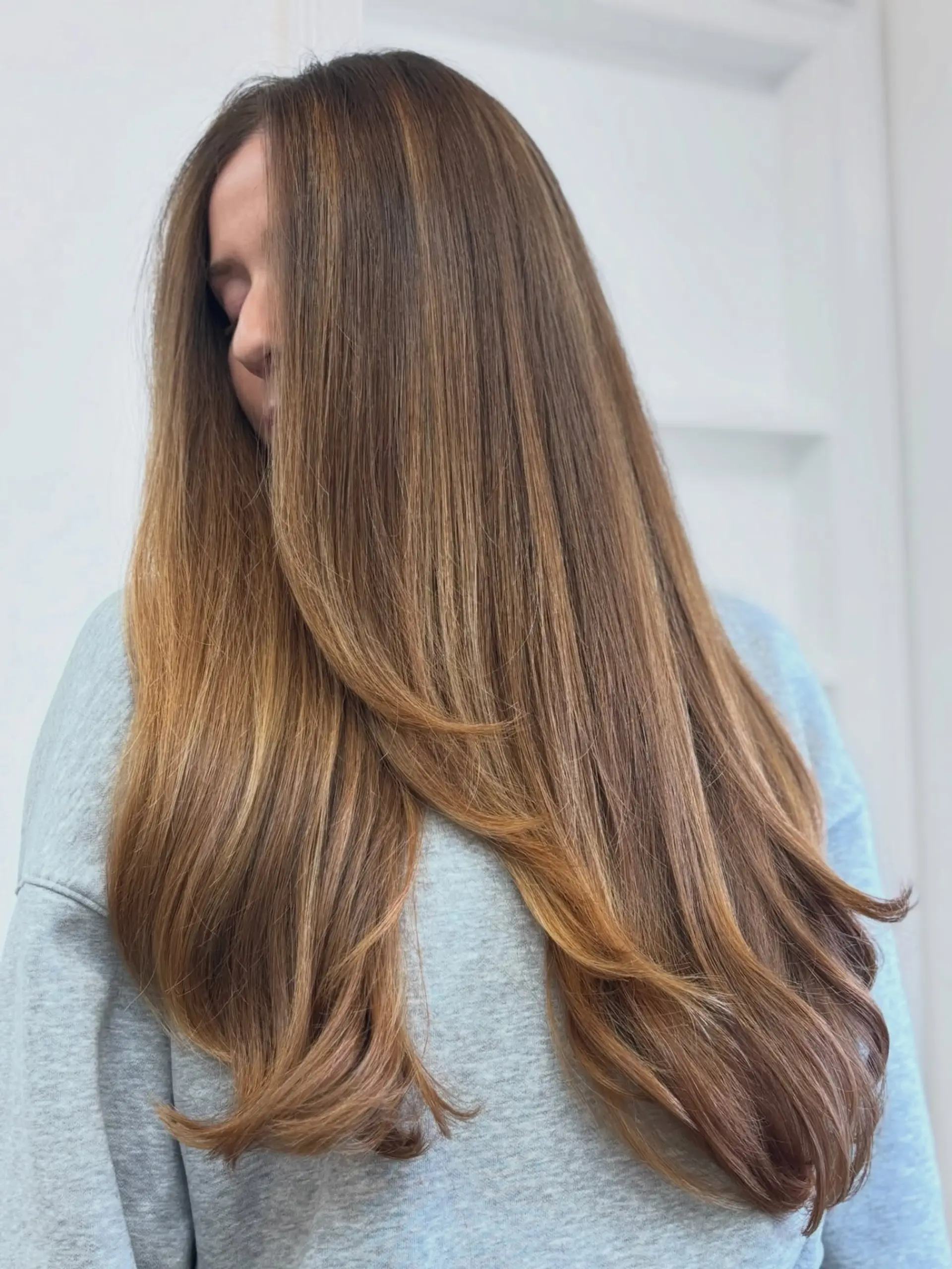 Extra-long, smooth brunette hair featuring blended caramel highlights and soft, face-framing layers. 1