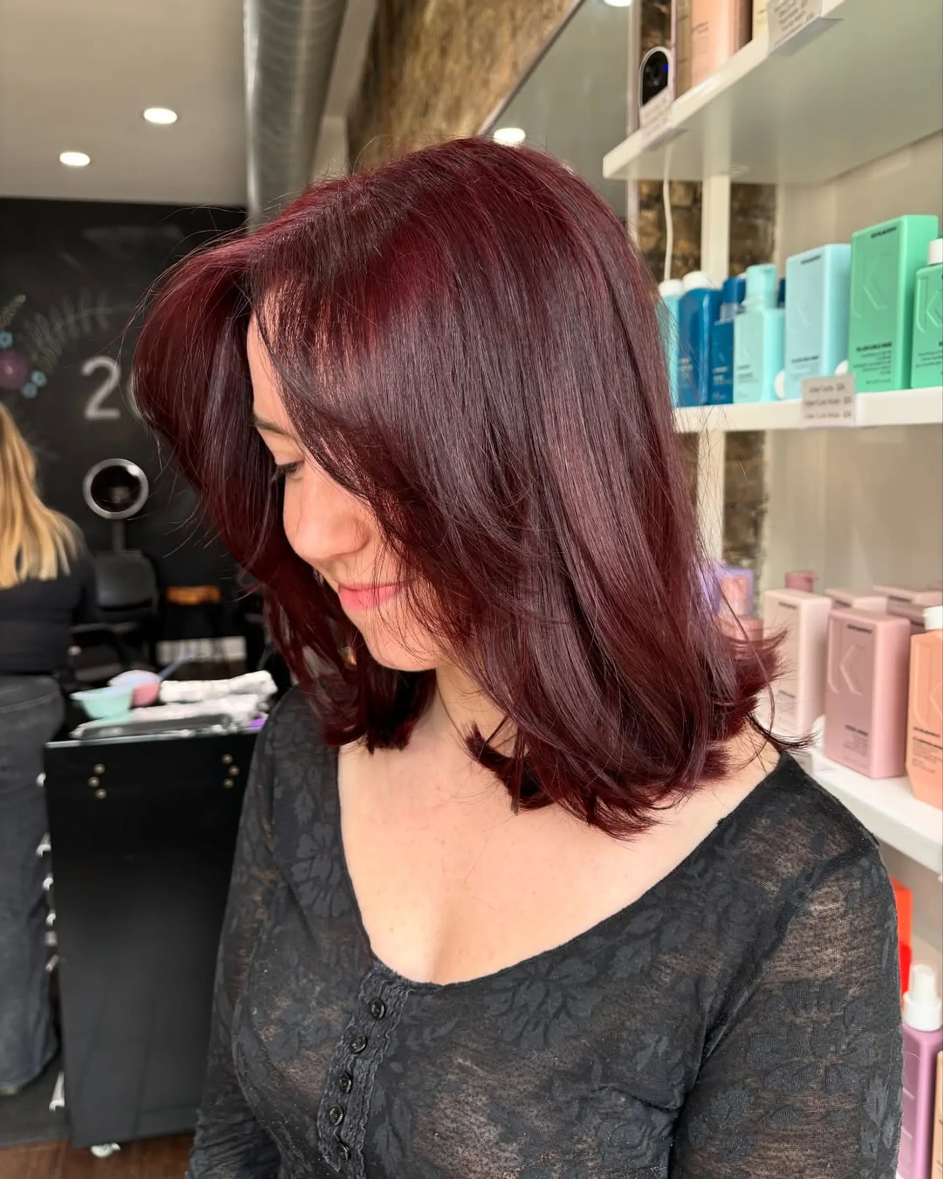 This chic lob features a medium length with gentle, face-framing layers that add movement and volume, complemented by a vibrant, deep cherry cola burgundy color for a bold and modern appeal. 1