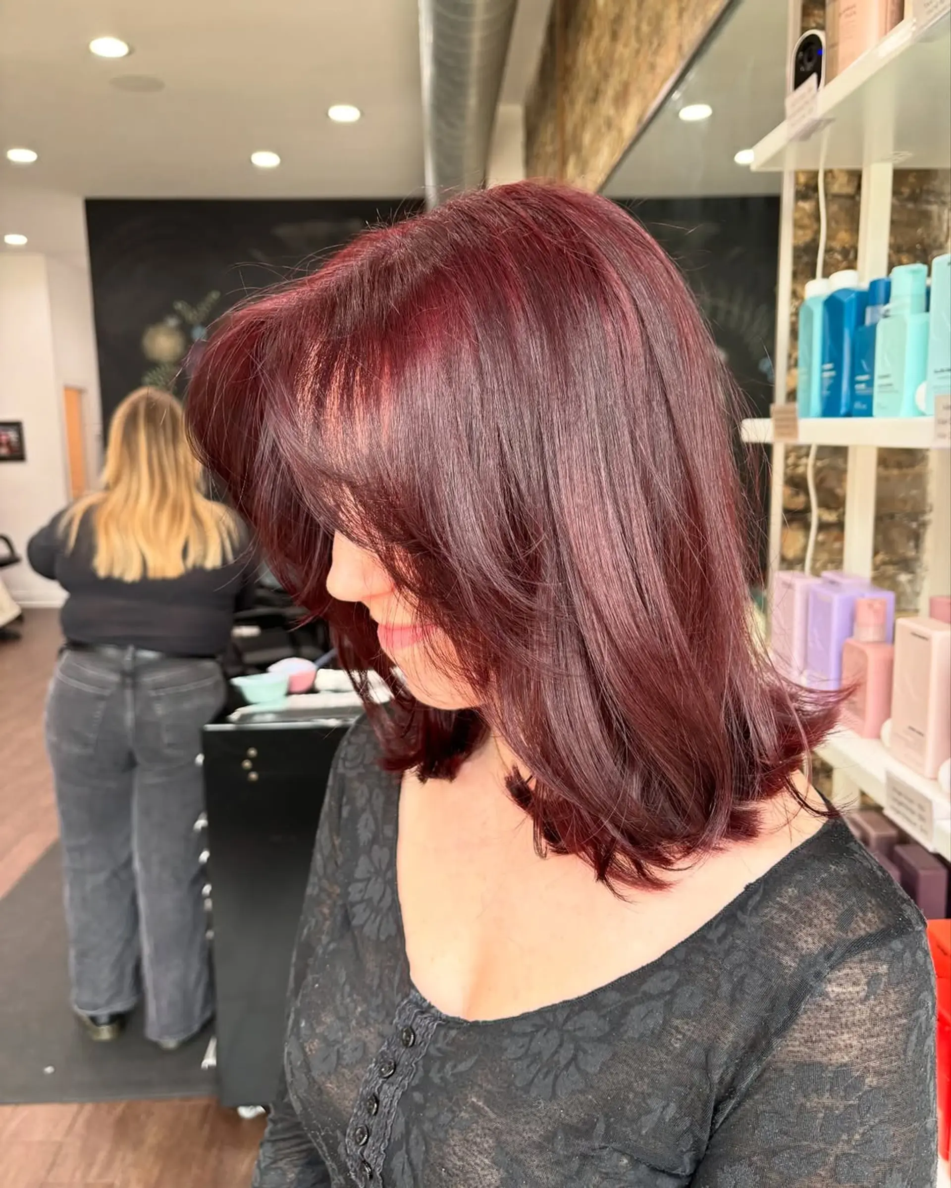 This chic lob features a medium length with gentle, face-framing layers that add movement and volume, complemented by a vibrant, deep cherry cola burgundy color for a bold and modern appeal. 2