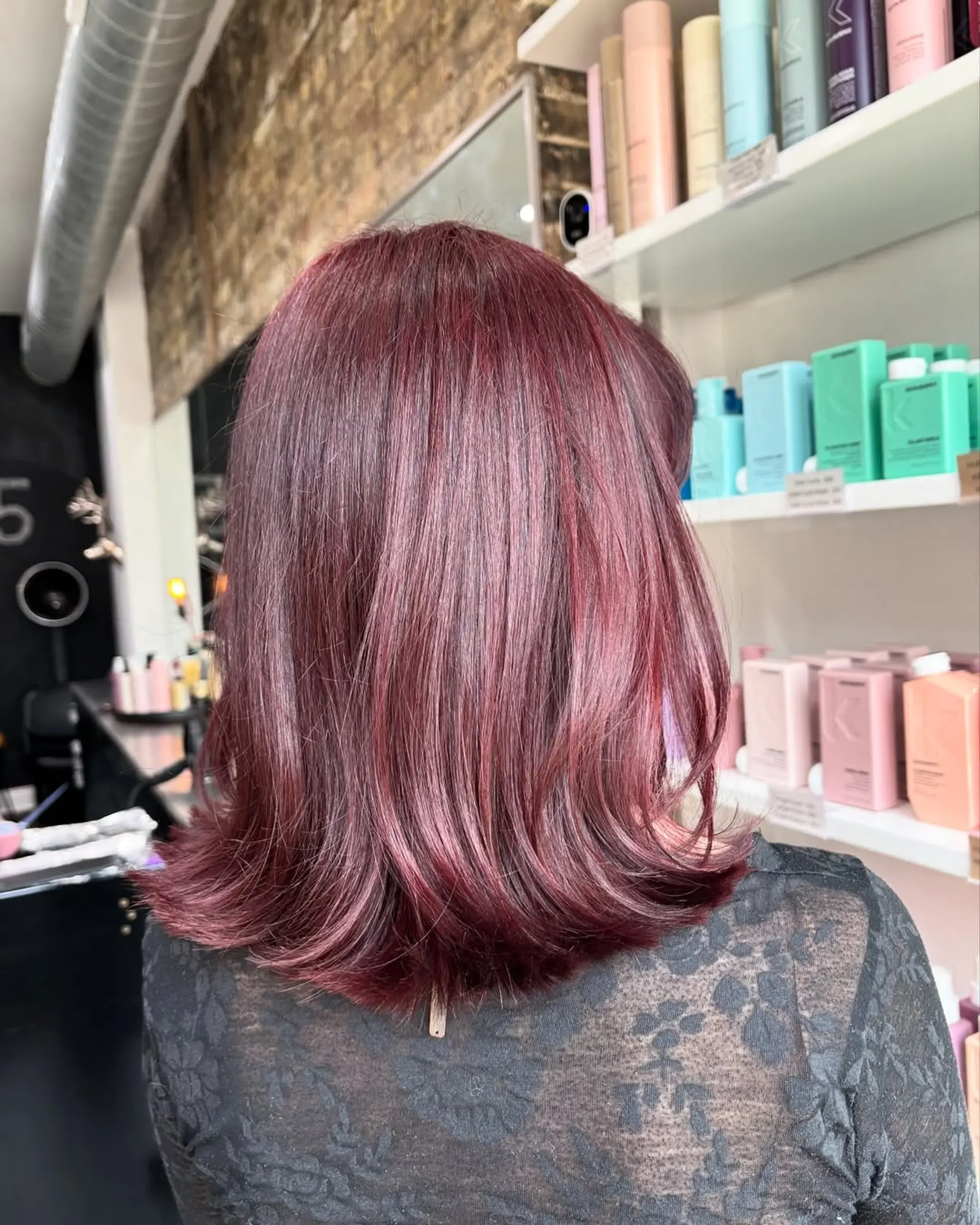 This chic lob features a medium length with gentle, face-framing layers that add movement and volume, complemented by a vibrant, deep cherry cola burgundy color for a bold and modern appeal. 3