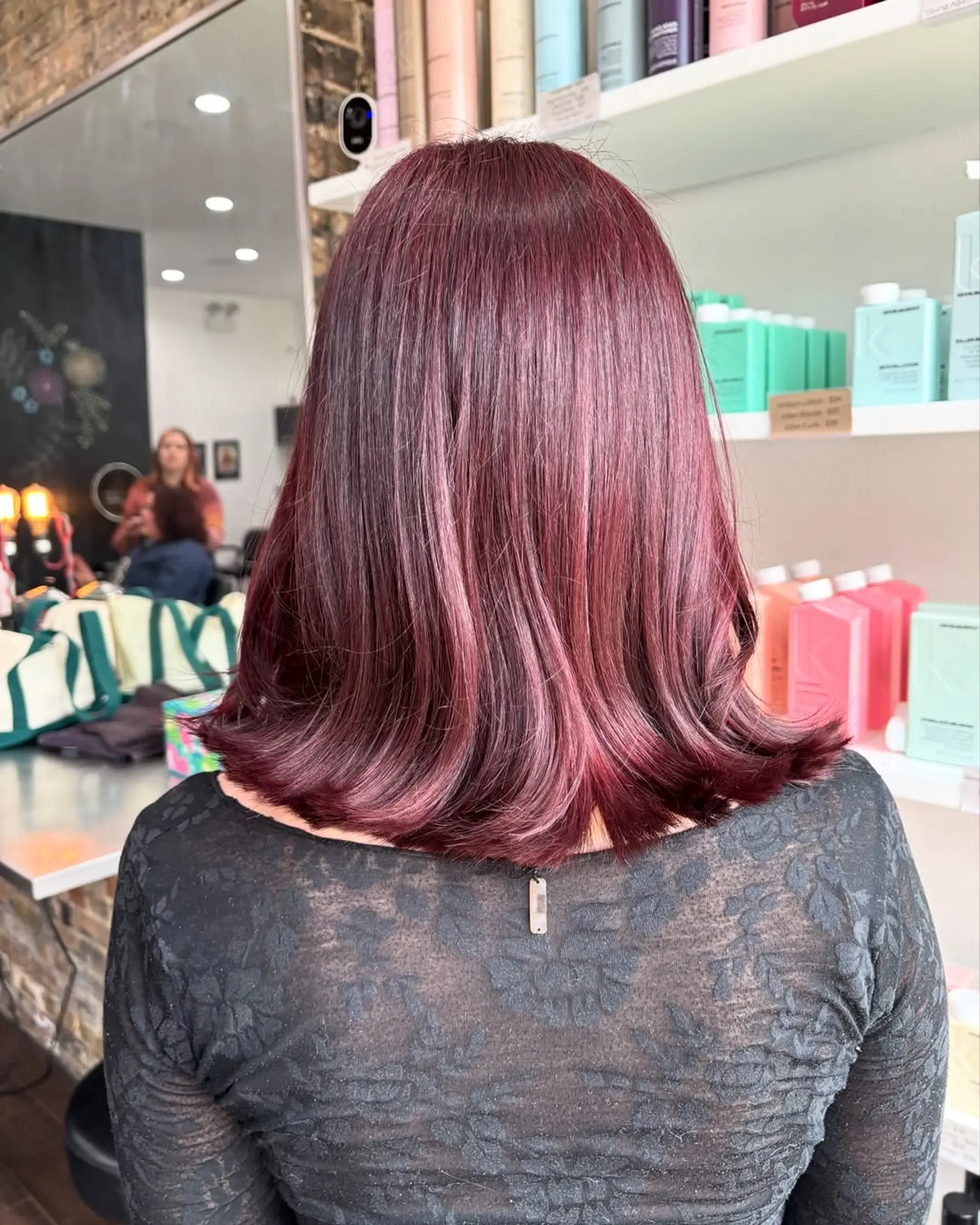 This chic lob features a medium length with gentle, face-framing layers that add movement and volume, complemented by a vibrant, deep cherry cola burgundy color for a bold and modern appeal. 4