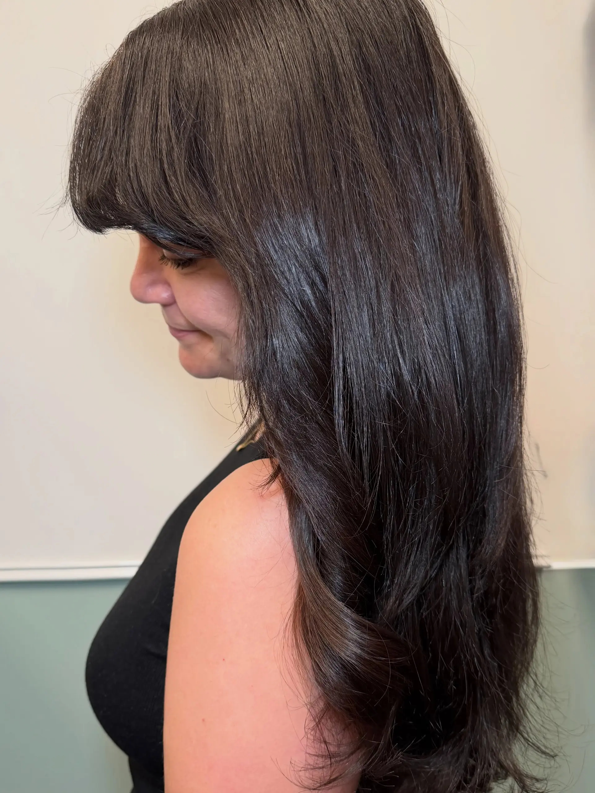 Long, ultra-glossy dark brunette hair styled smooth with heavy front bangs and soft curved ends. 1