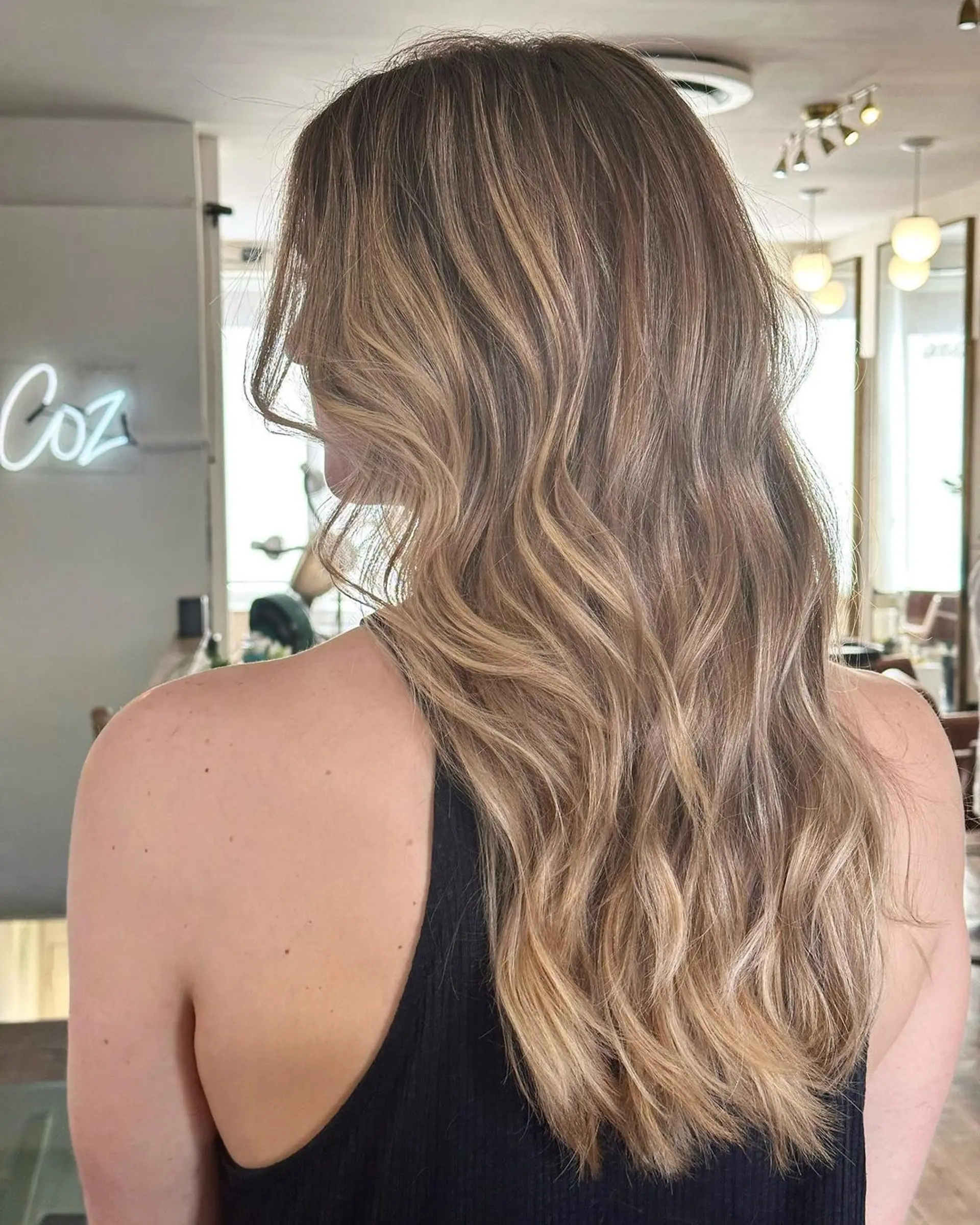 Long, wavy hair with sunlit blonde and honey highlights, featuring subtle layers and a naturally flowing texture. 1