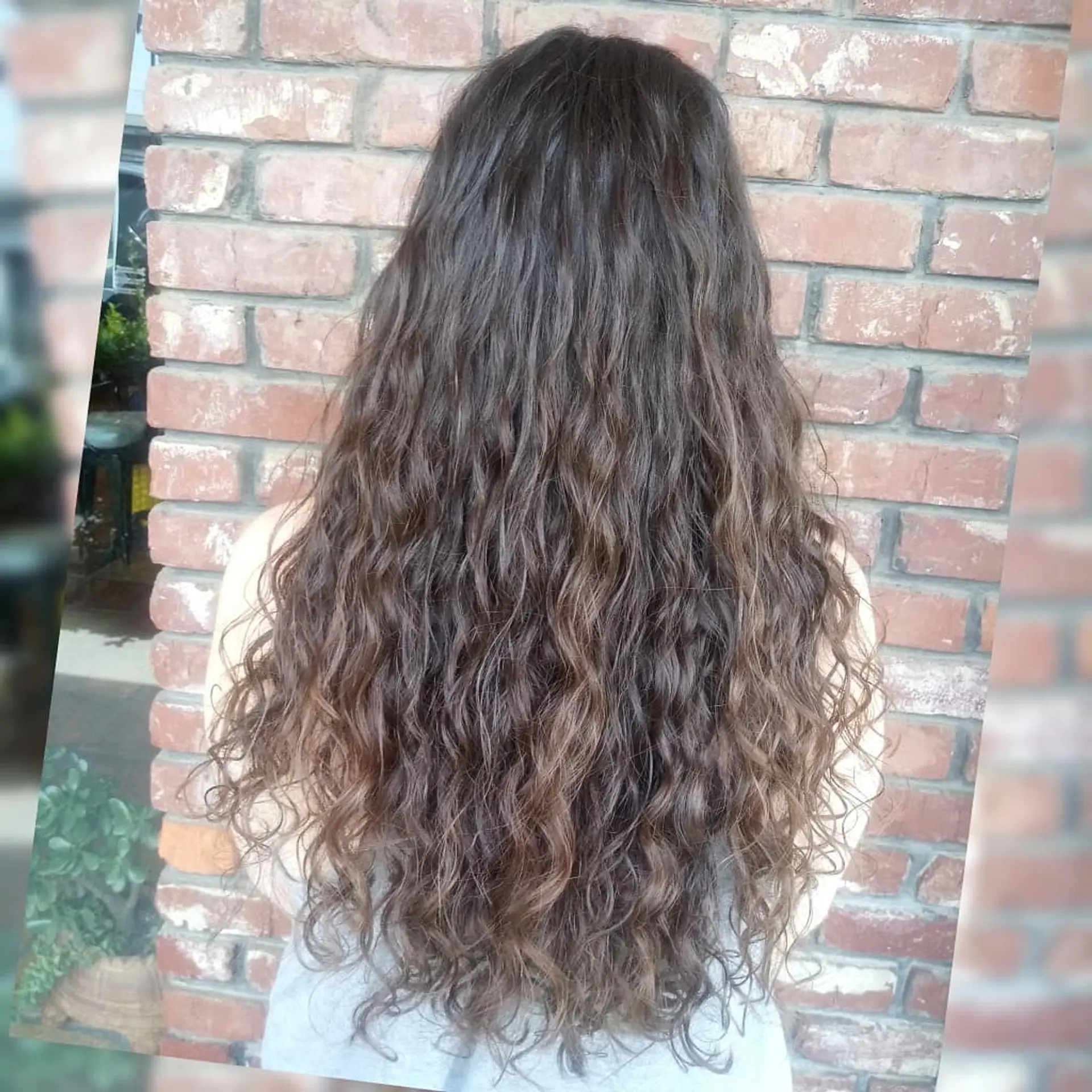 Extra-long brunette hair styled in defined, natural waves and loose curls cascading down the back. 1