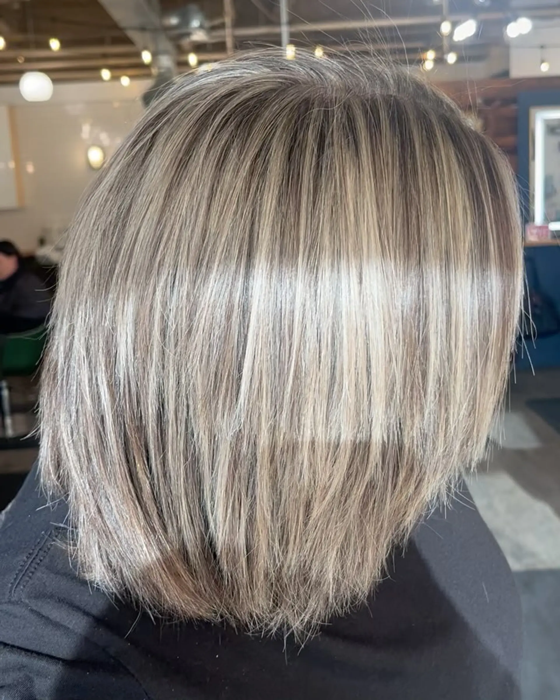 A textured, shoulder-length layered bob with dimensional cool-toned highlights seamlessly blended over a natural base. 1